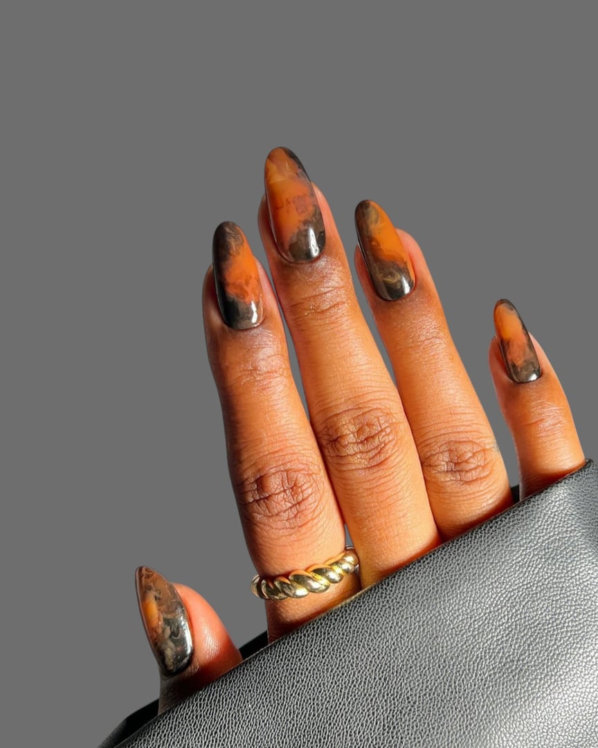 A detailed close-up of a young woman's hands featuring a modern manicure with a unique nail art style. The design combines elegant shapes, trendy colors, and creative details to reflect a fresh and fashionable look. This contemporary nail art highlights individuality, beauty, and self-expression, making it ideal for concepts related to fashion editorials, beauty industry promotions, nail salons, and skincare or lifestyle campaigns. The clean background and professional finish emphasize the artistic quality of the manicure, giving the image a refined and stylish appeal.