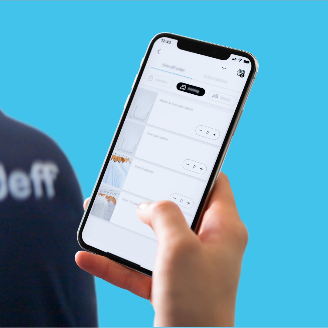 Person holding smartphone with a laundry service app open, showing options for clothing care against a blue background.