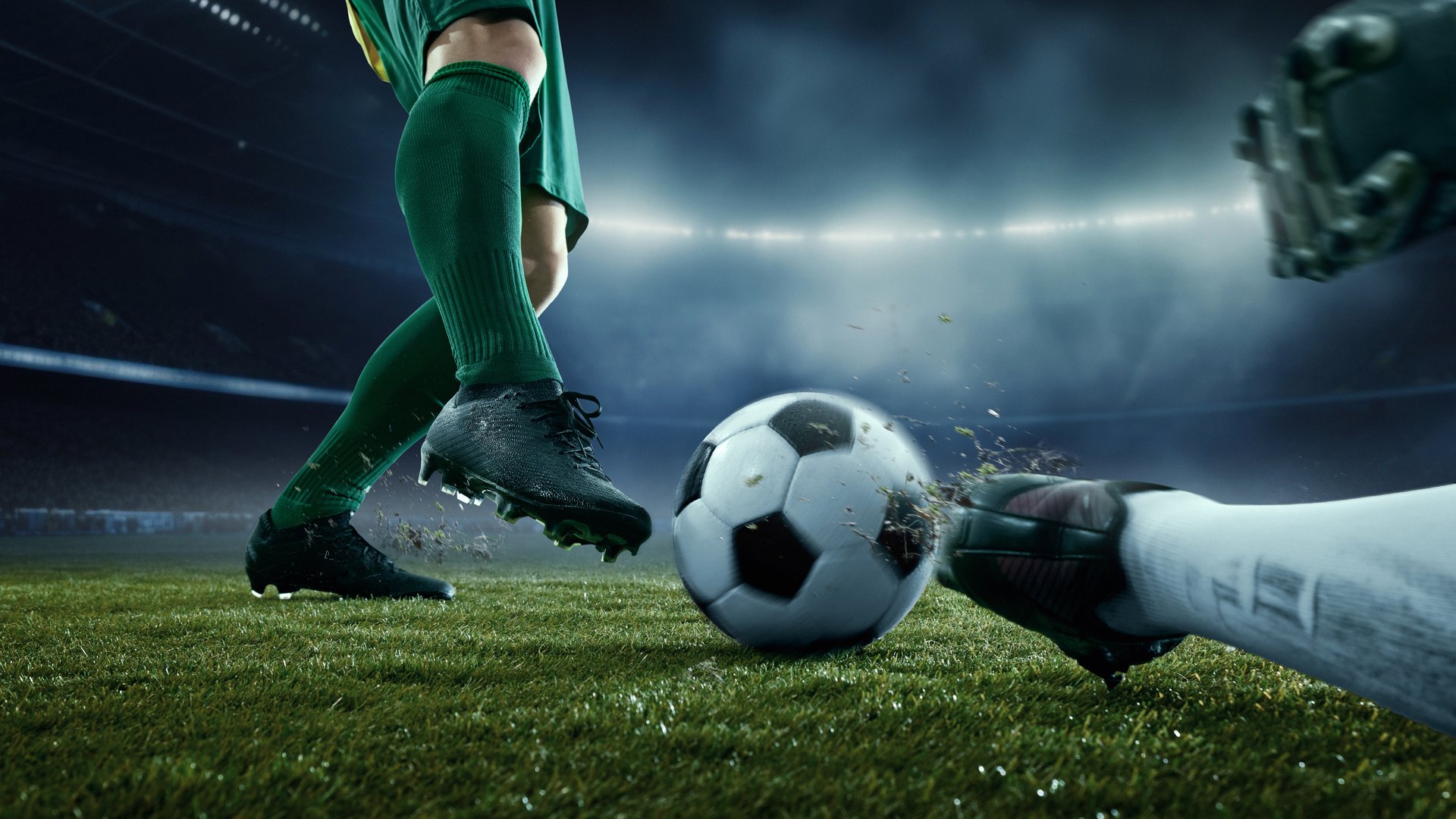 Player in green uniform maneuvering soccer ball while goalkeeper in white-green lunges to stop in high-stakes match under bright stadium lights. Concept of sport championship, match, tournament. Ad
