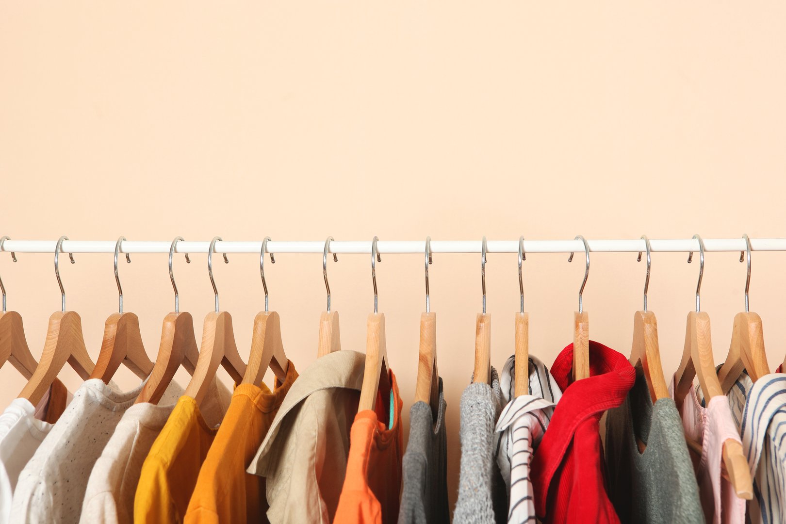 Fashionable clothes on hangers on a wardrobe rack.
