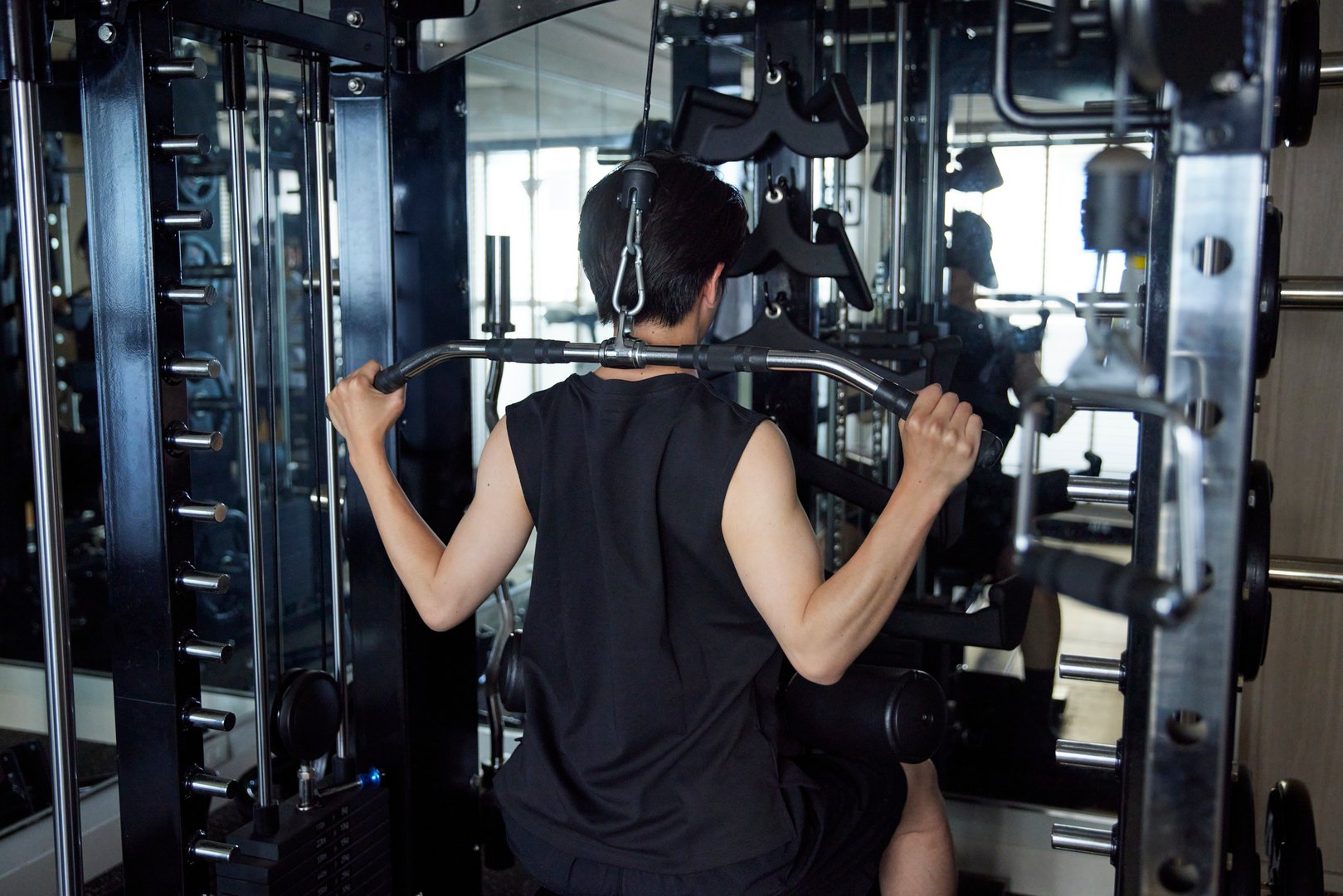 Young Japanese man in sportswear doing strength training at a fitness gym