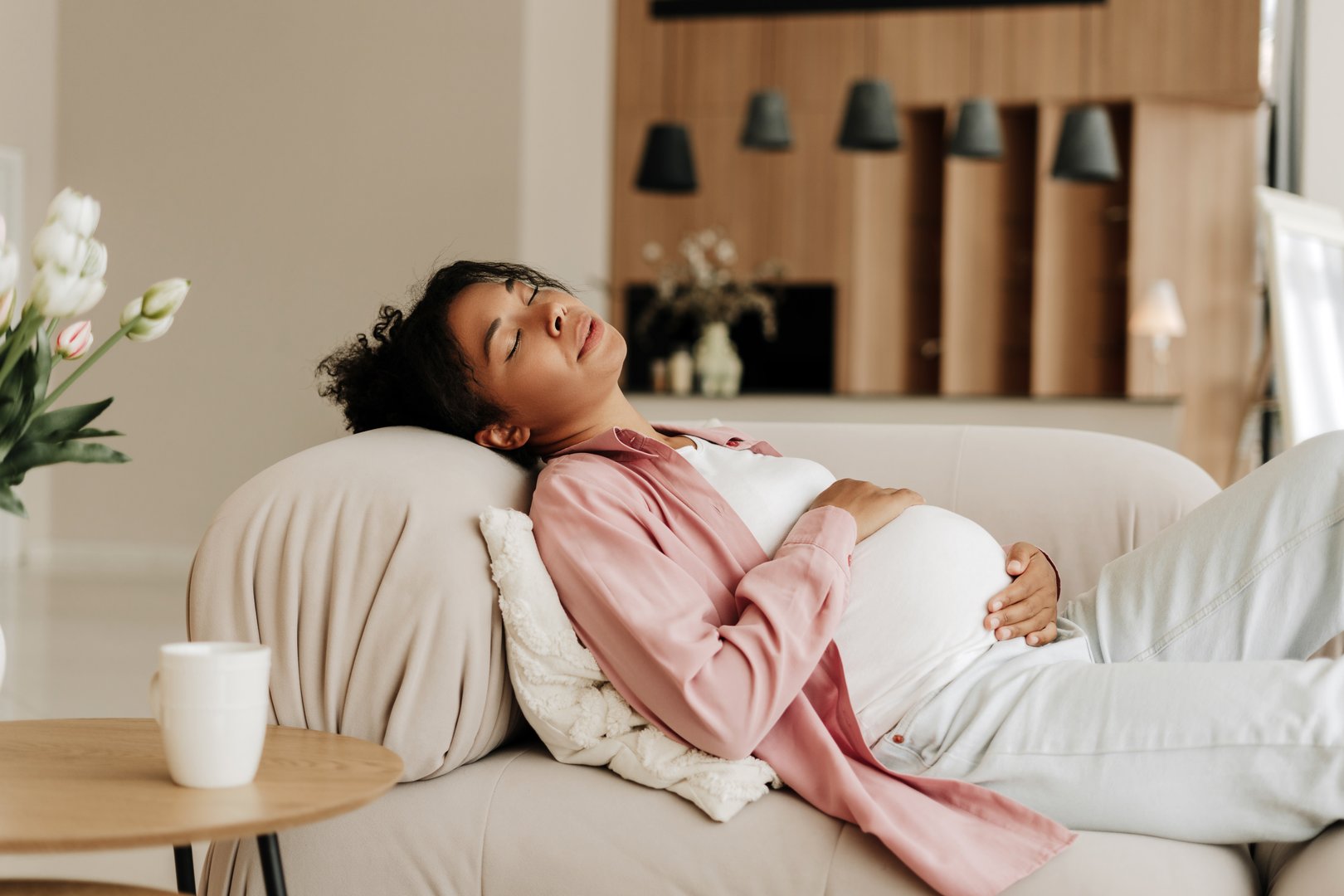 Pregnant woman is napping on a comfortable sofa, enjoying a moment of peace and quiet at home