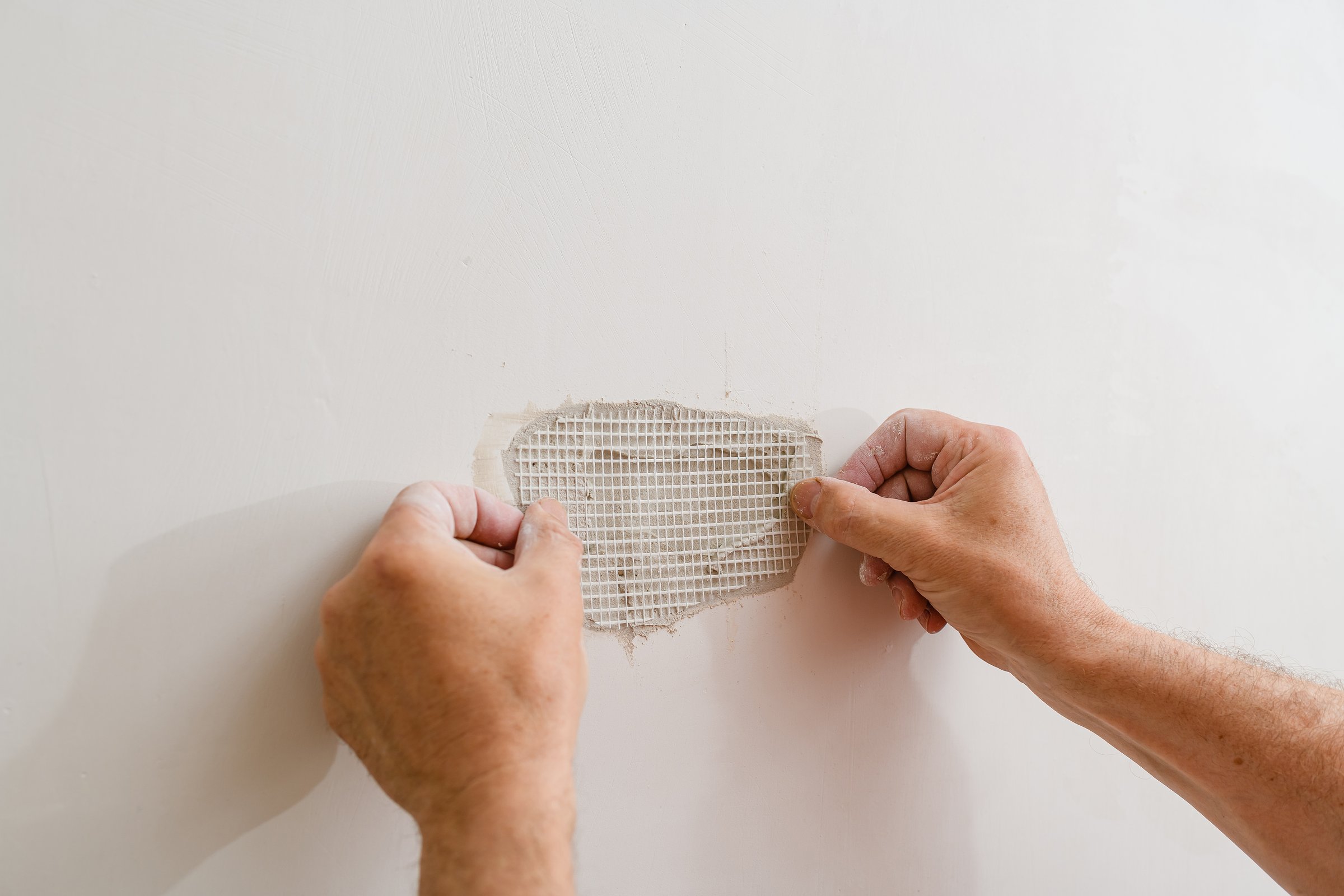 Repairing holes in drywall. A handyman is repairing a hole in the drywall in the wall.