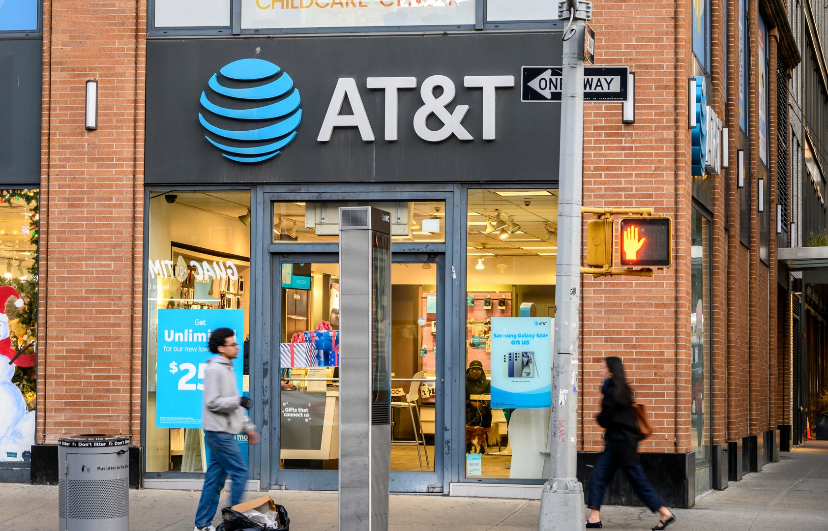 New York, New York, USA - November 18, 2024: People can be seen walking on Sixth Avenue in front of the AT&T store.