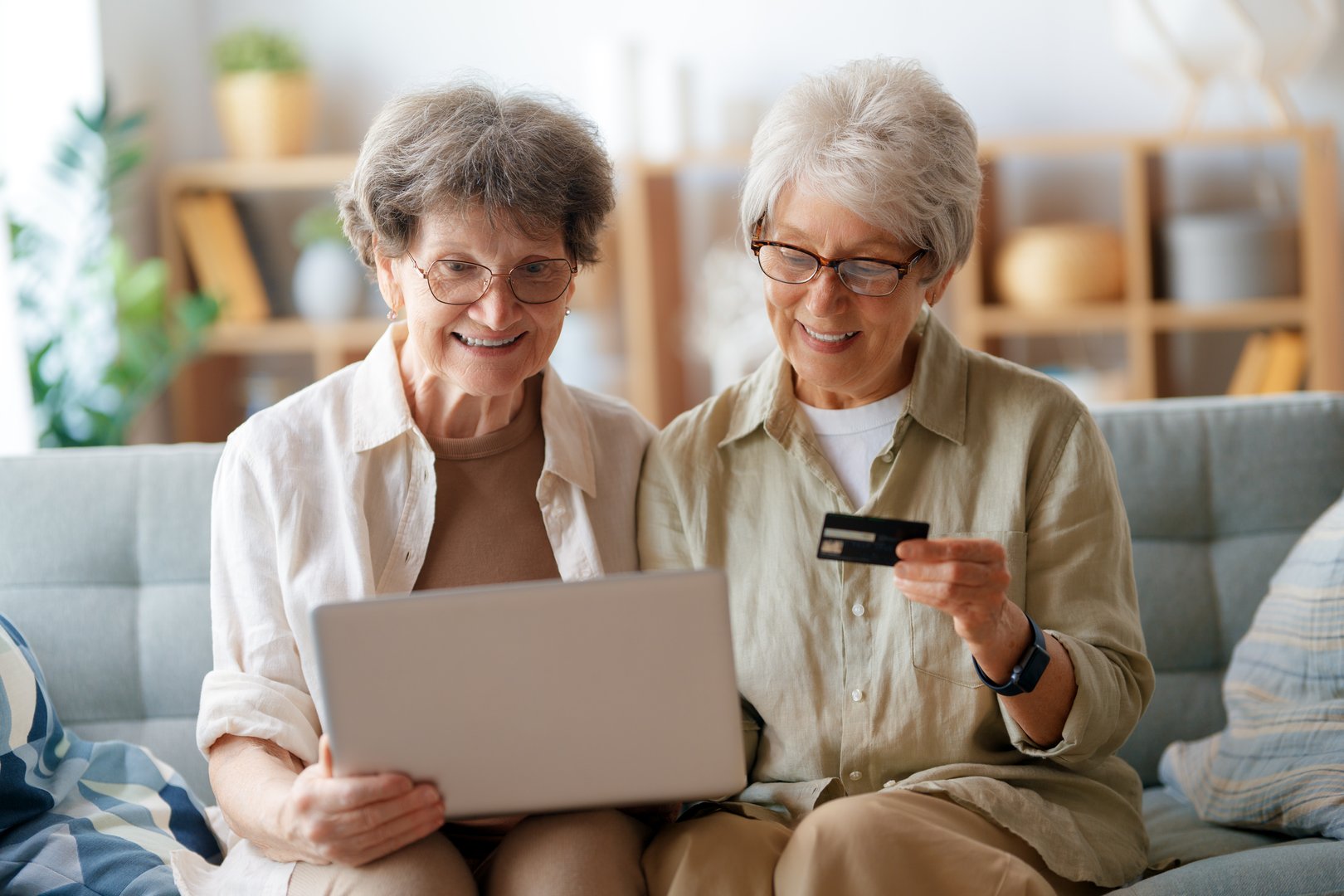Women are doing online purchases. Senior people are doing shopping using laptop and credit card at home.