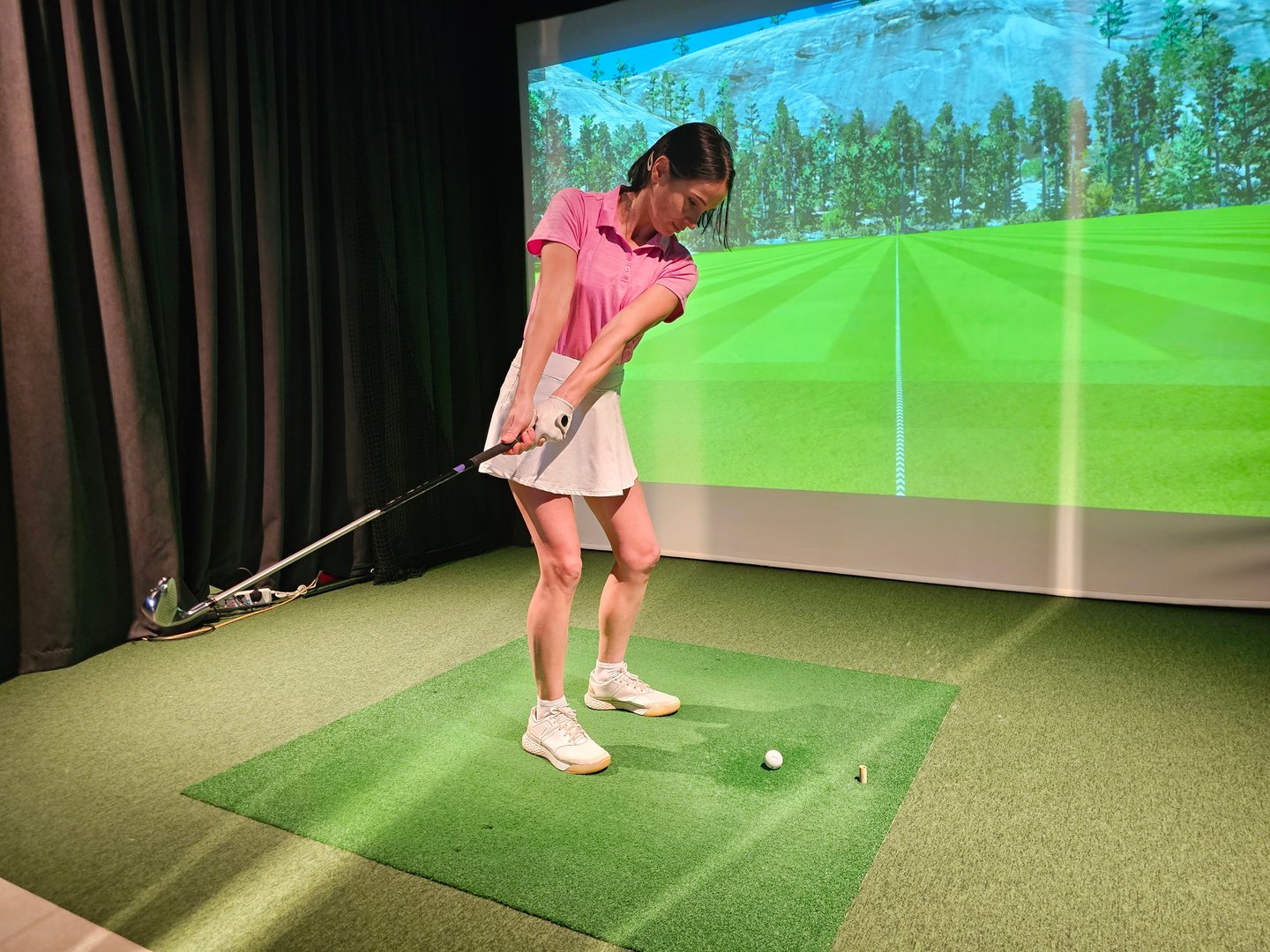Golf practice session indoors with a player using a swing simulation in a realistic setting