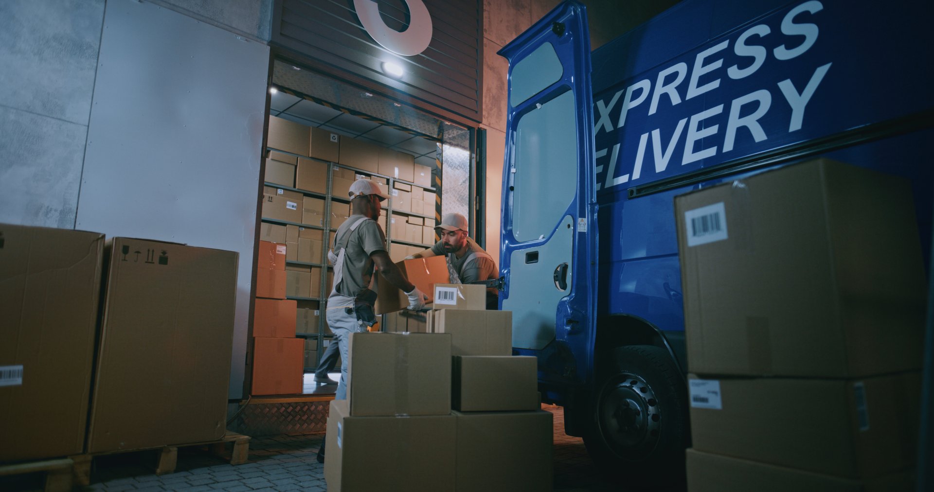 Multiethnic Workers Loading Cardboard Boxes with Online Orders, E-Commerce Goods in Truck for Shipment, Working in Express Delivery Service at Night. Outside of Logistics Retail Warehouse. Full Shot.