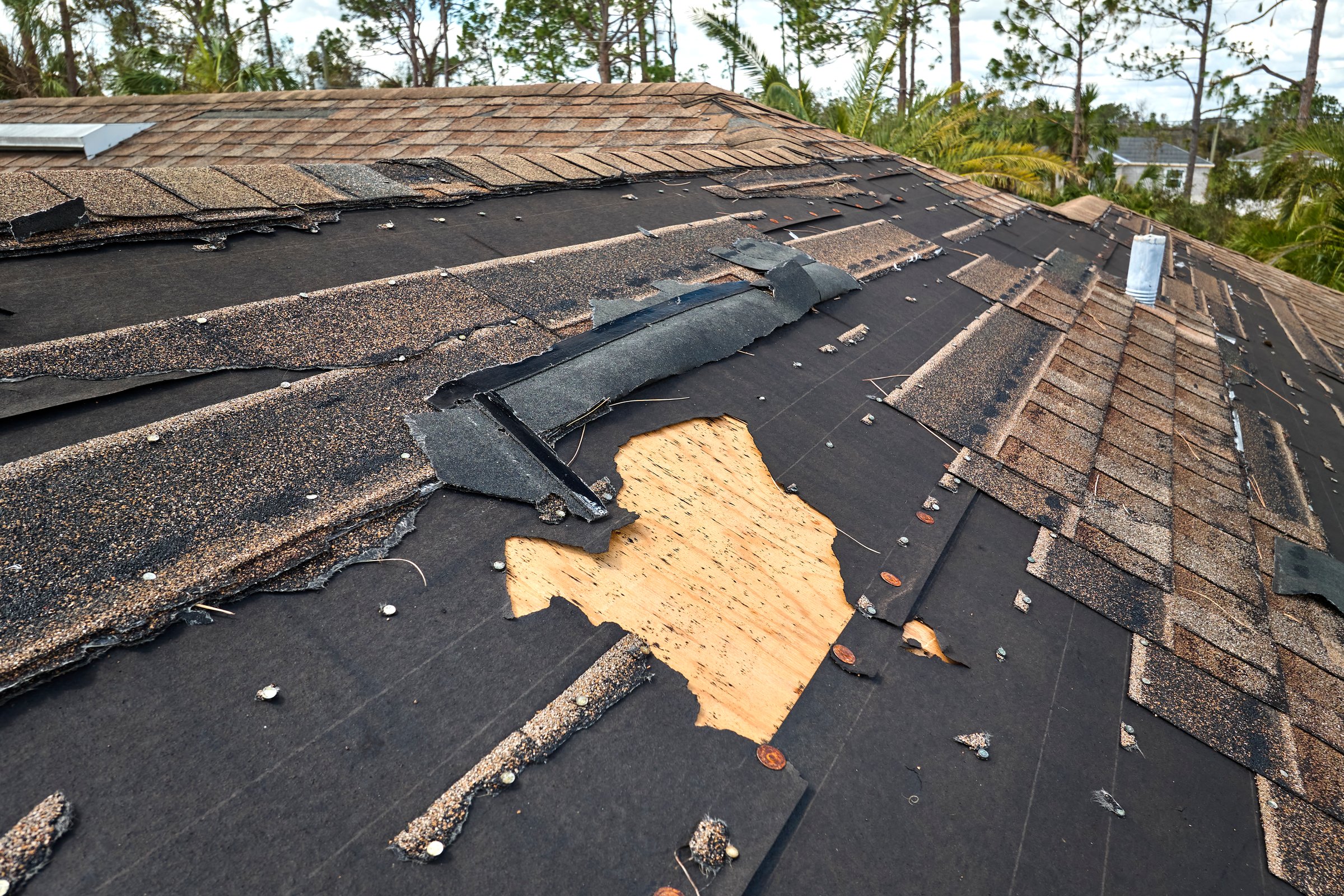 Damaged house roof with missing shingles after hurricane Ian in Florida. Consequences of natural disaster.