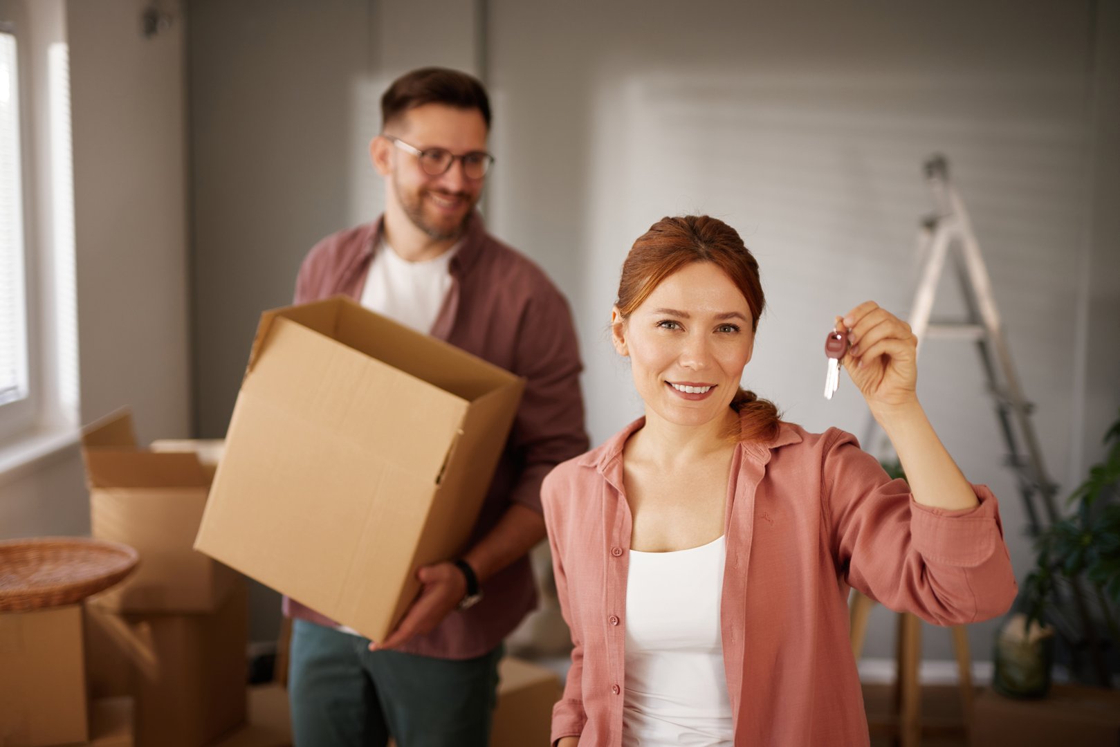 Happy couple holding new house keys and moving boxes: new home, new beginnings