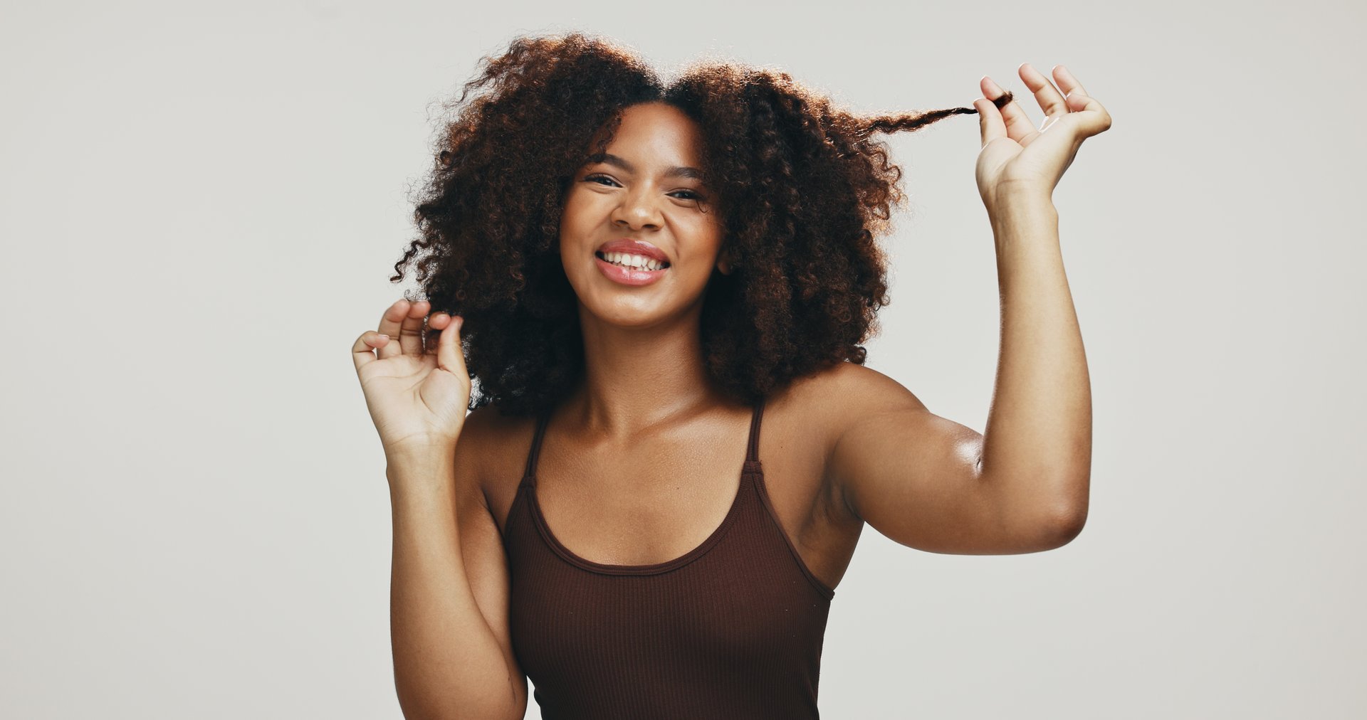 Happy, afro or black woman for hair care, texture and glow for portrait, volume and natural shampoo. Studio, pull or model with beauty, smile and growth for cosmetics and results by white background