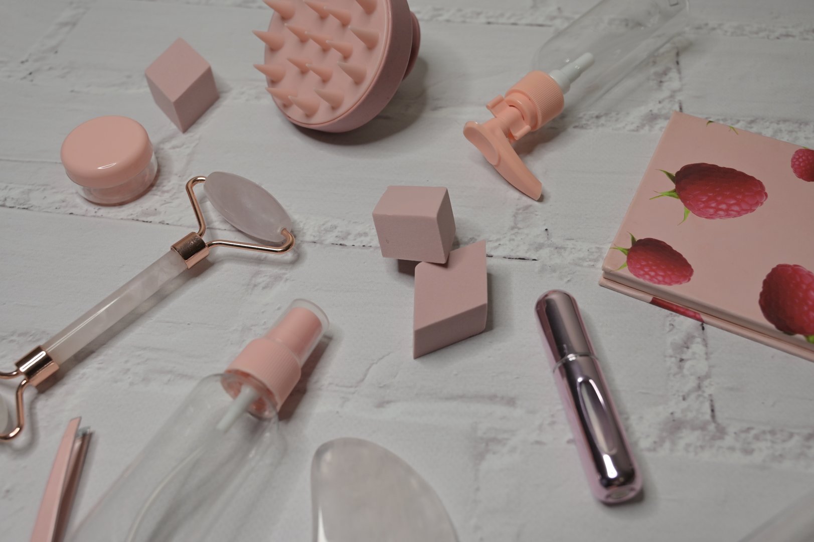 Scattered pink female cosmetic trinkets for skin care and lymphatic drainage face massage with gouache, white background