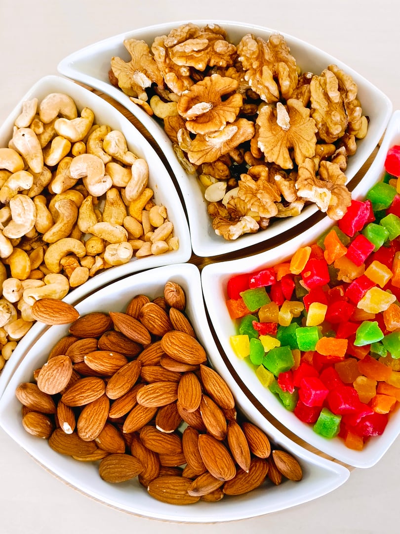 A plate with different nuts: walnuts, cashews, almonds and candied fruits. Close-up, vertical photo.