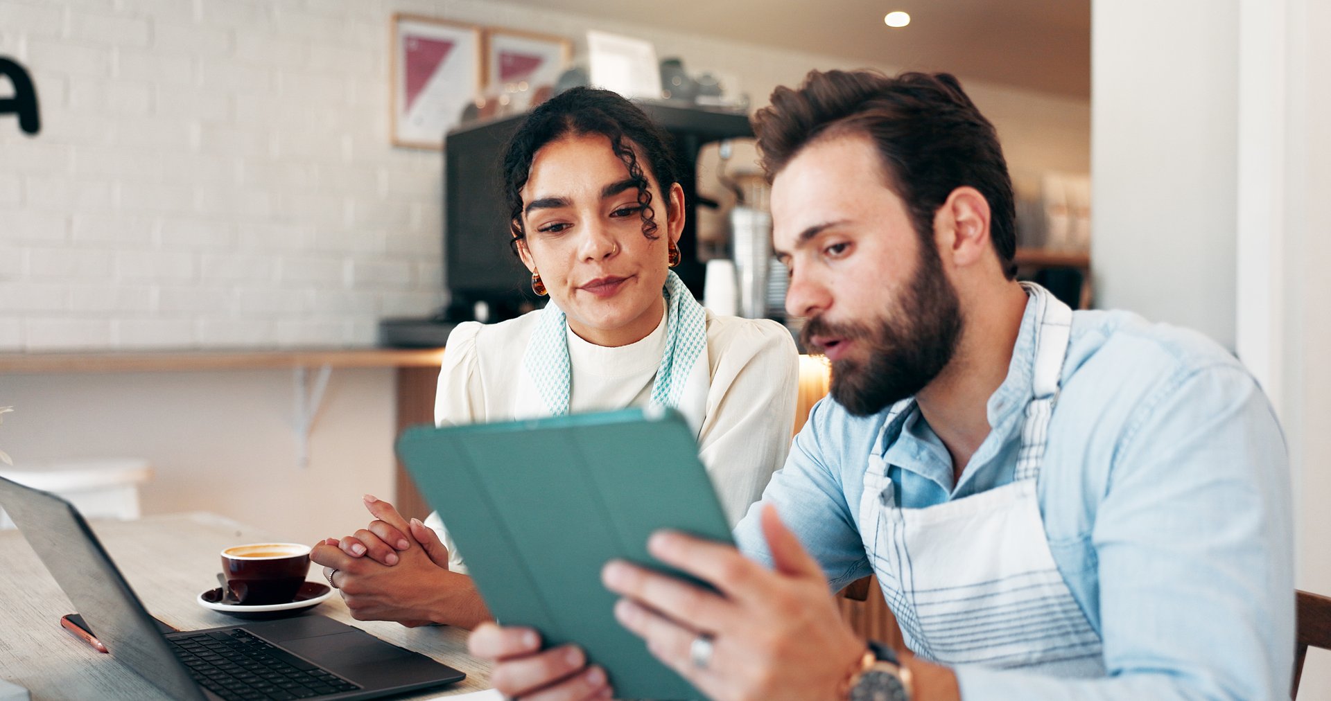 Business people, tablet and teamwork in cafe for review, social media and retail management notes. Owner, meeting and laptop in coffee shop for sales report, restaurant profit or hospitality deal
