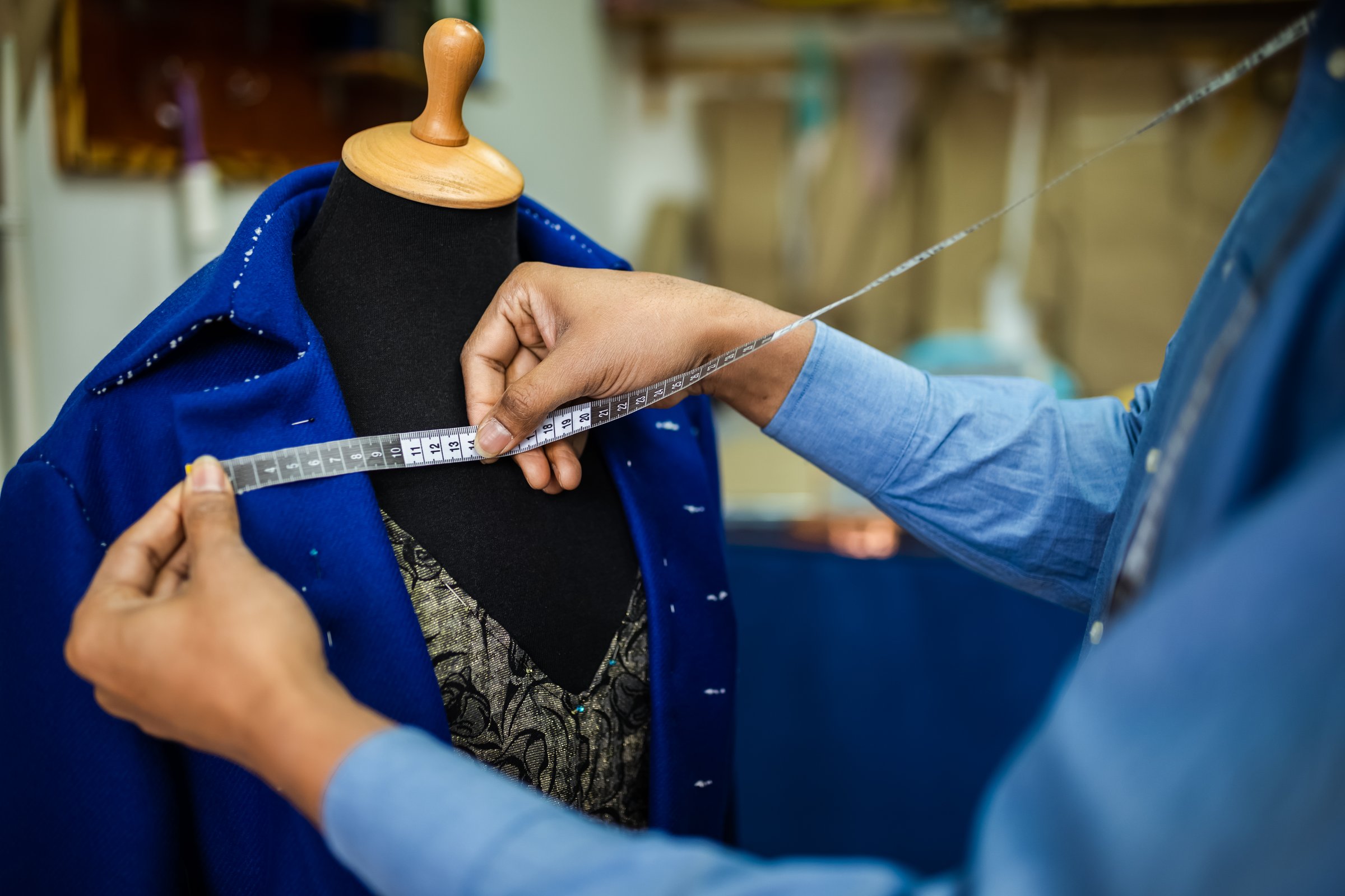 African American men fashion designer,tailor measuring jacket, blazer in his atelier.