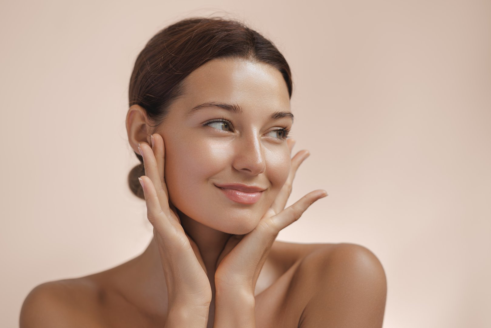 Happy beautiful young adult woman showing her perfect face with healthy shiny skin. Beauty photo of gorgeous girl after morning beauty cosmetic routine finishes daily makeup on pink background. Youth and skin care concept. High-quality studio photo