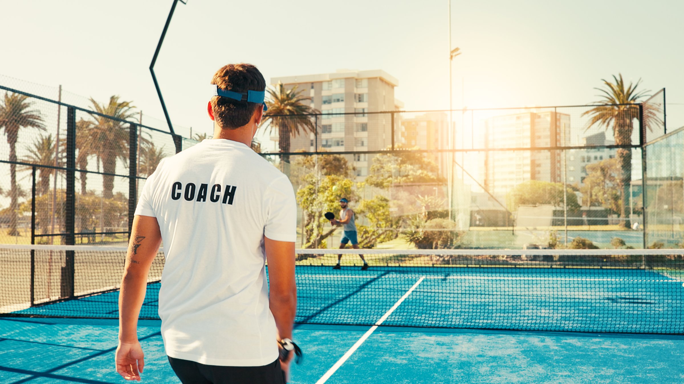 Back, coach and man with training, tennis and lesson with fitness, workout and hobby. Professional trainer, instructor or athlete with court, practice or technique development with exercise or health