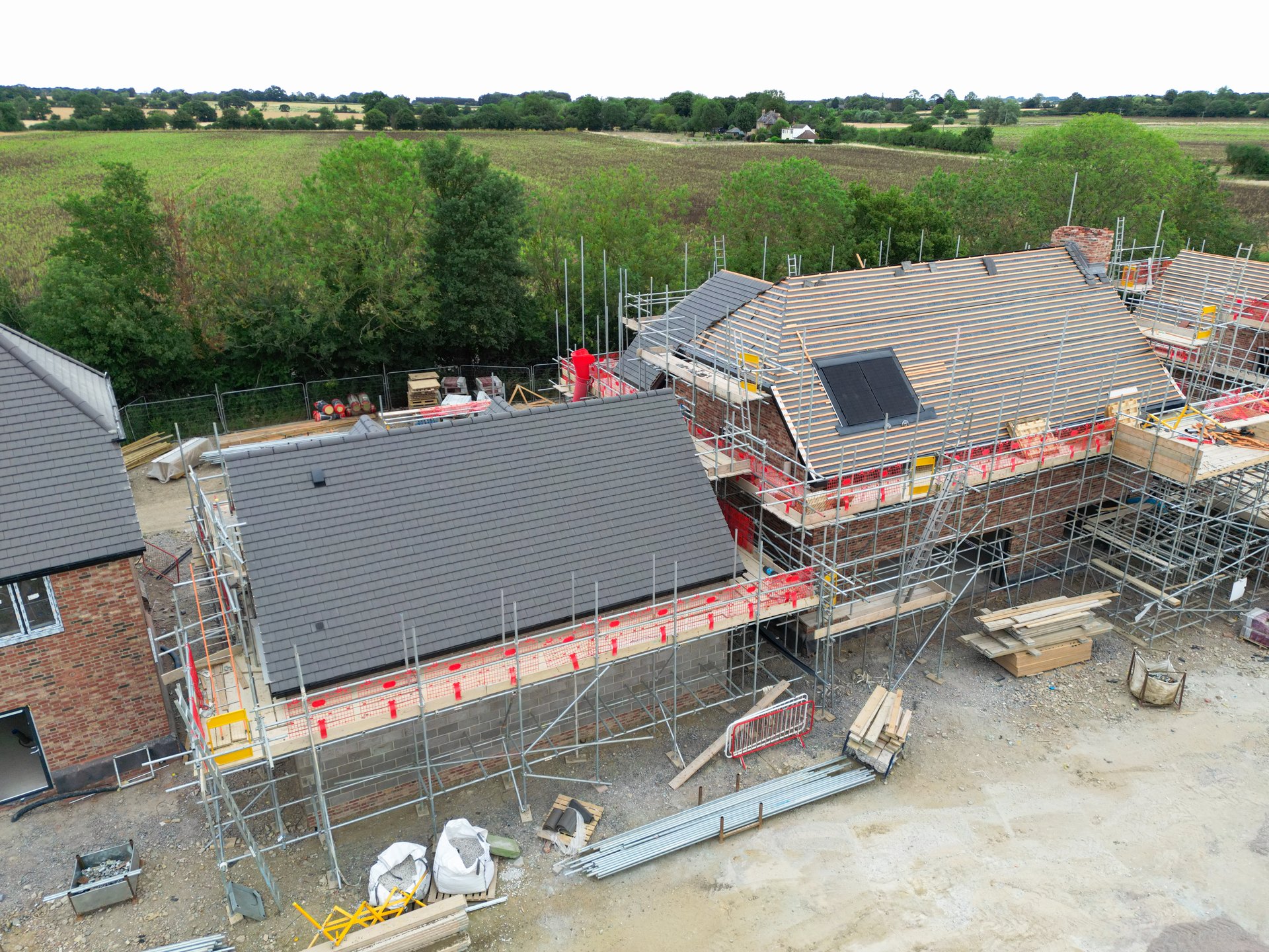 Unusual drone view of new roofs been fitting to family homes within a British housing development site. Seen with some solar panels.
