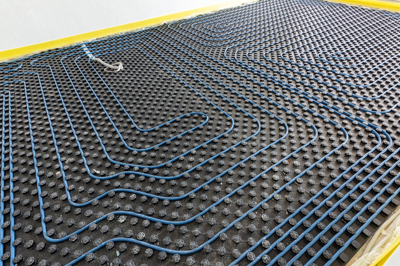 System of underfloor heating. Installation of a heat flooring system. Modern heating system in a new home
