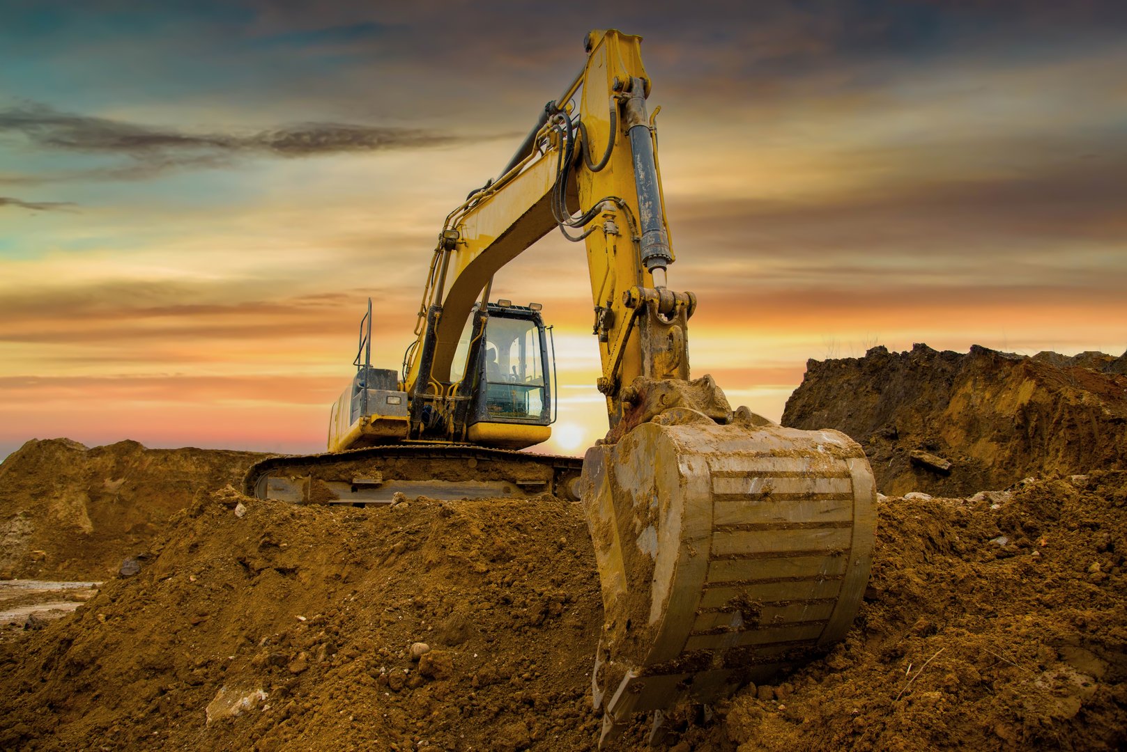 Excavator on sunset. Open-pit mining. Backhoe dig ground in quarry. Heavy construction equipment on excavation on construction site. Excavator on groundworks. Construction machinery on Earthworks.