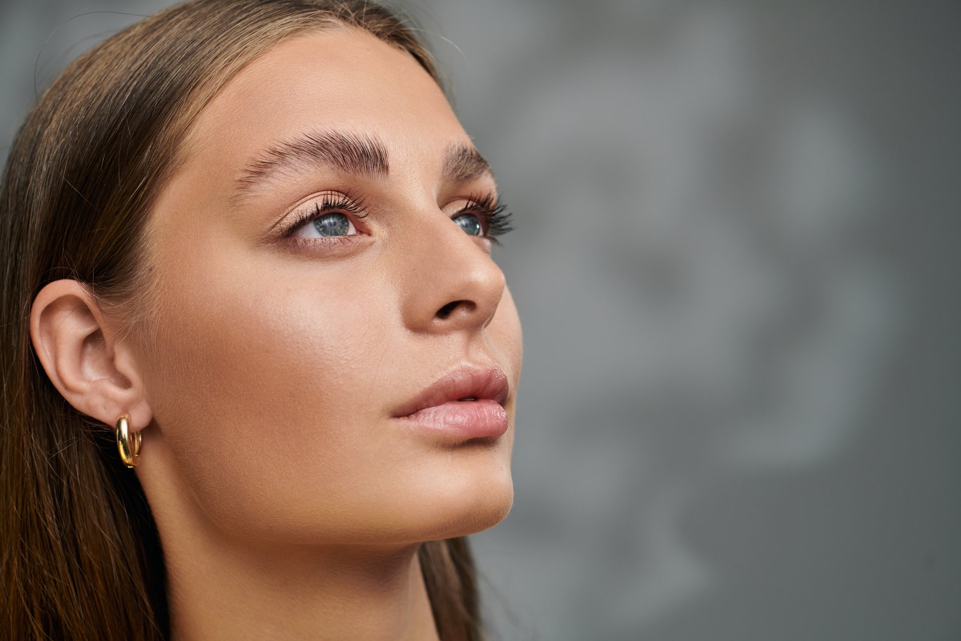 Young woman with tan skin and natural makeup showcases her beauty in a relaxed studio setting.
