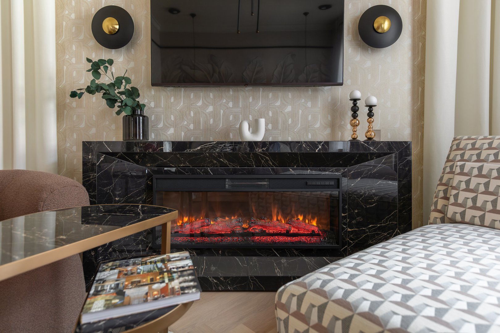 Stylish electric fireplace with glowing embers framed by black marble, surrounded by contemporary furniture and warm, patterned textures.
