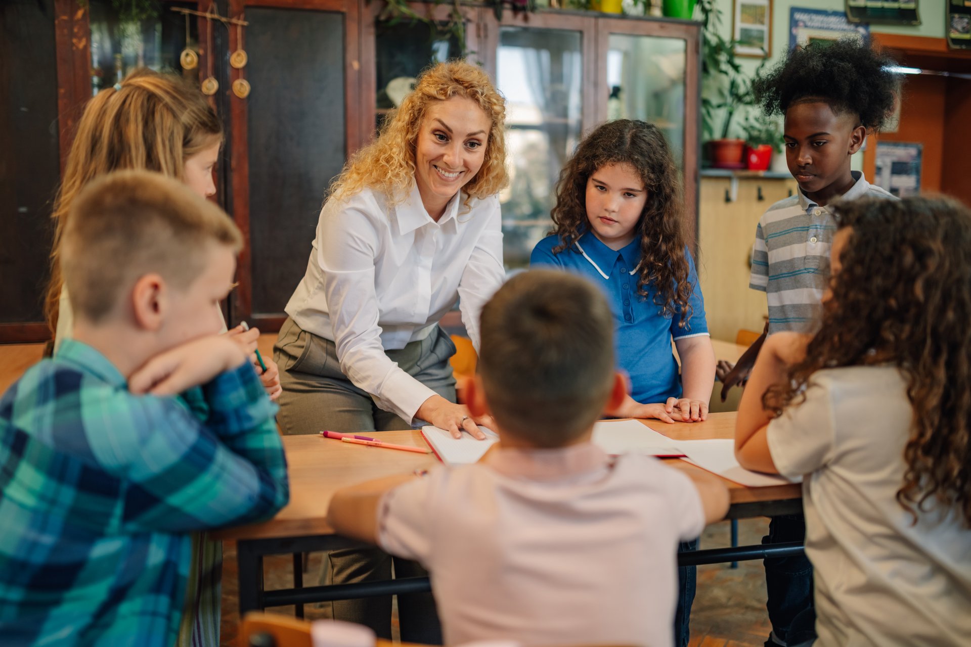 Elementary school teacher engaging with a diverse group of students, explaining lessons and fostering a collaborative learning environment