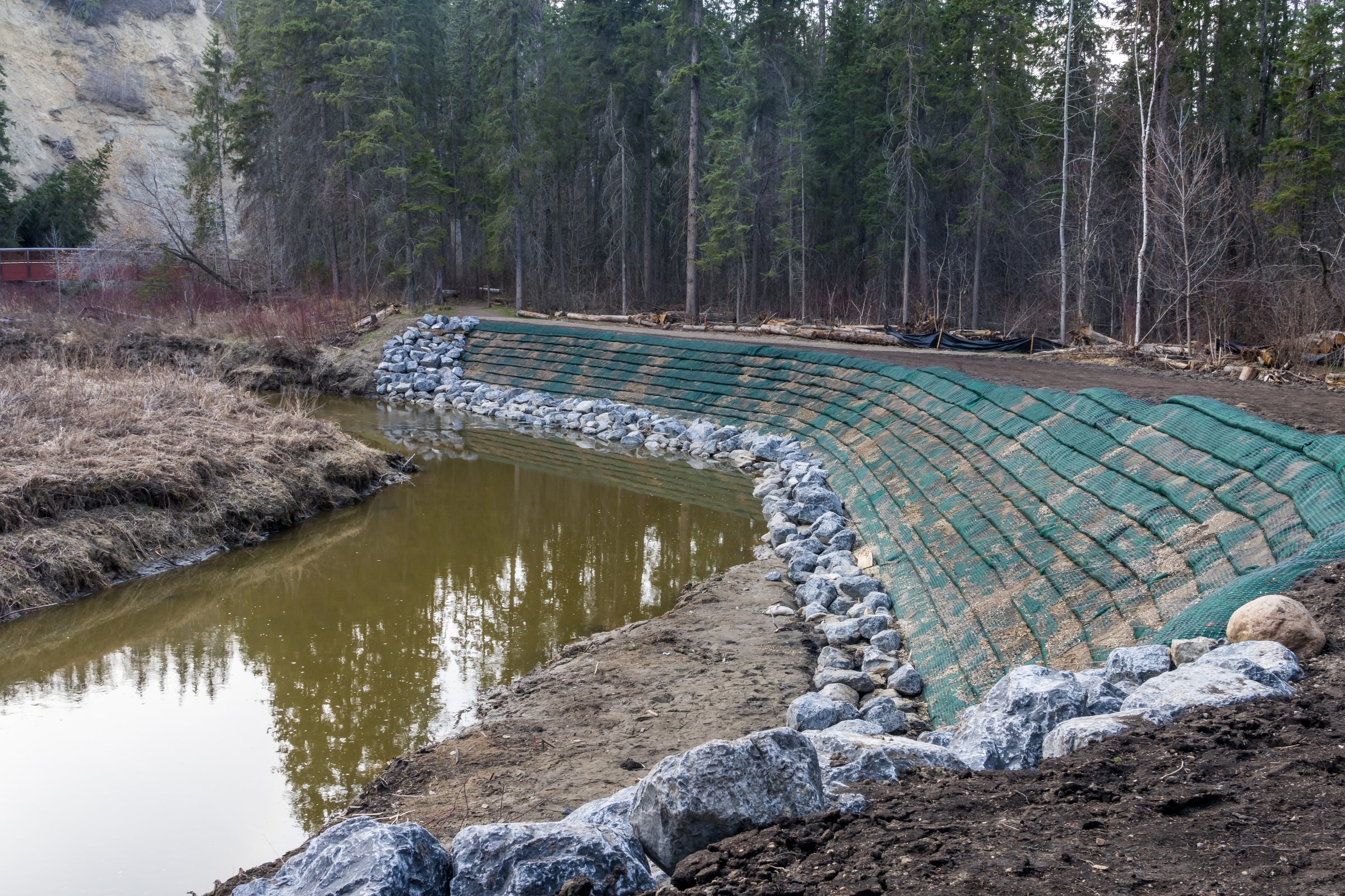 Erosion control project at Whitemud creek, Edmonton, Alberta with fortification of river bank with rocks and green color plastic net
