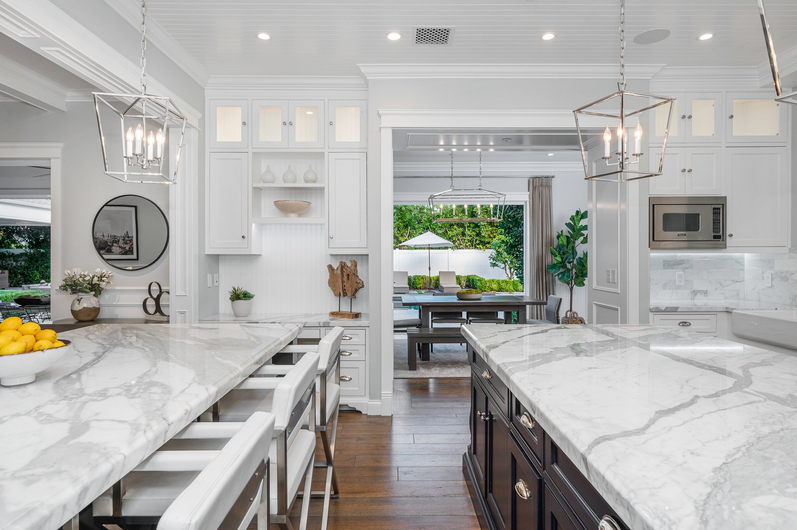 A marble kitchen with a white island, and chairs in a new construction home in Encino, California