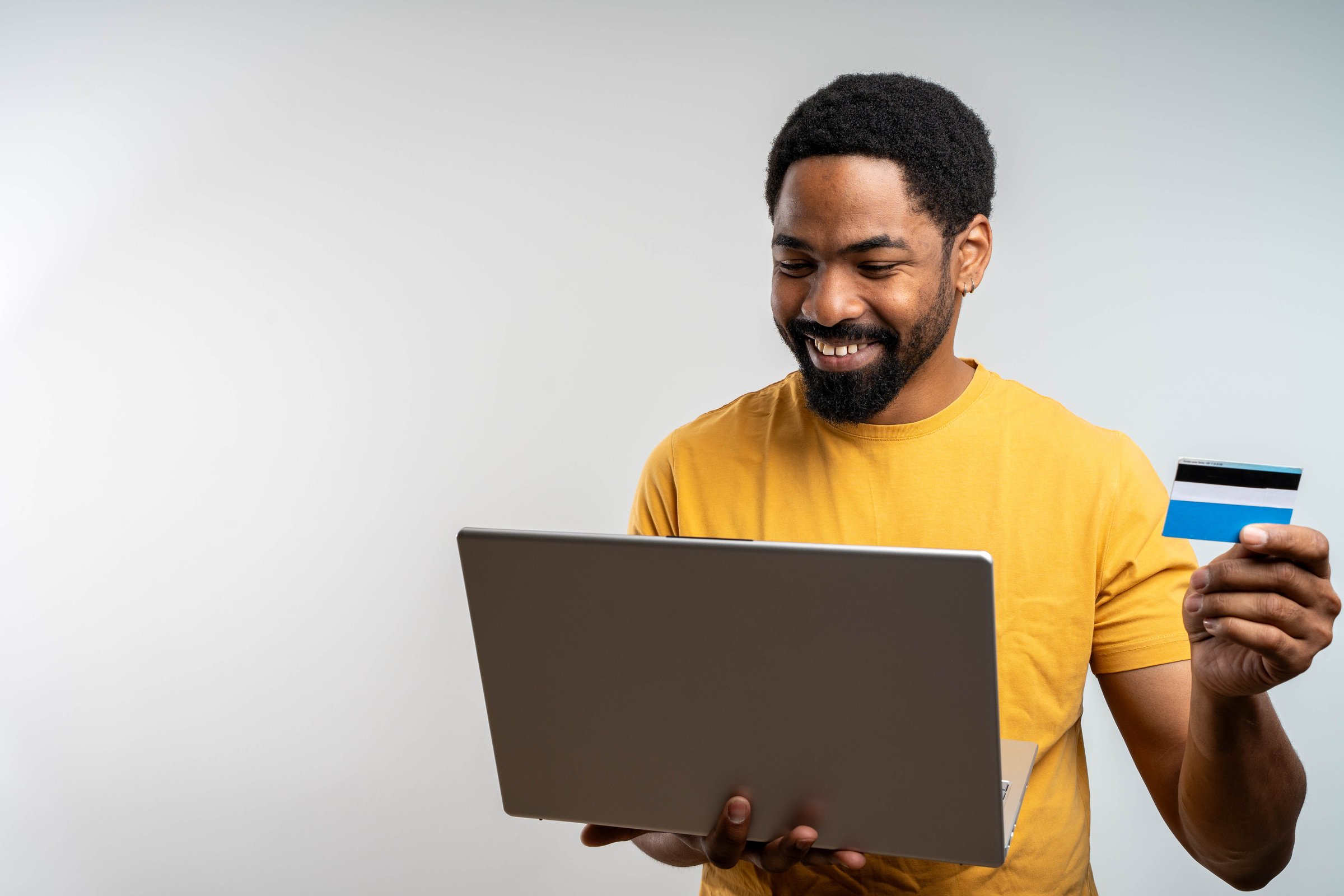 Happy cheerful smiling young adult man doing online shopping or e-shopping satisfied entrepreneur making online pay