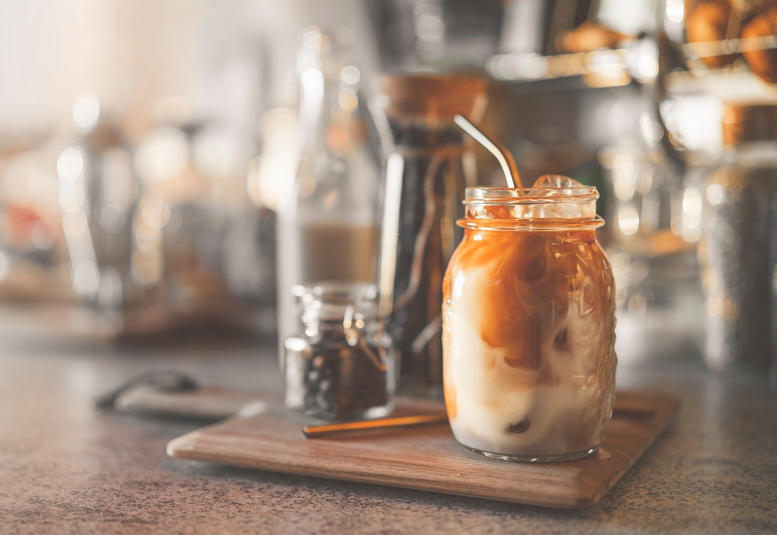 A woman is making iced coffee at home in the kitchen during the day.