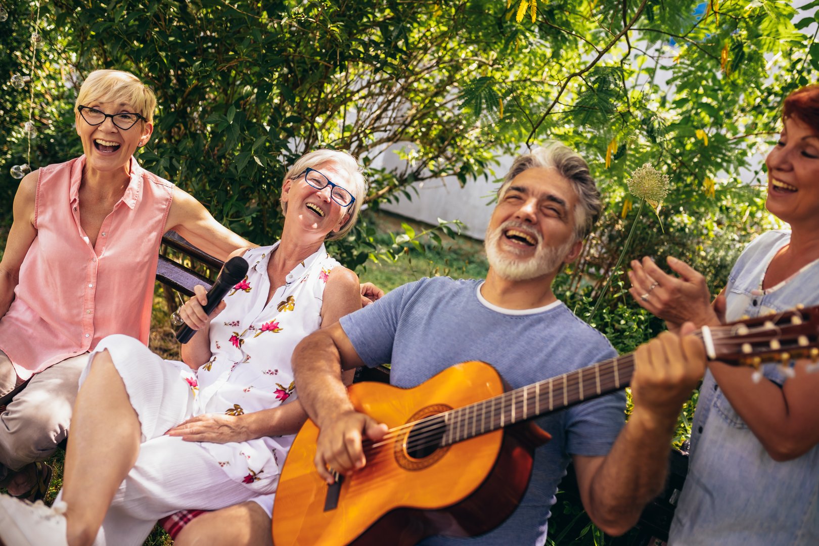 Group of elderly people enjoying their retirement by going on a picnic, playing a guitar and singing, making barbeque, making memories and making their friendship stronger