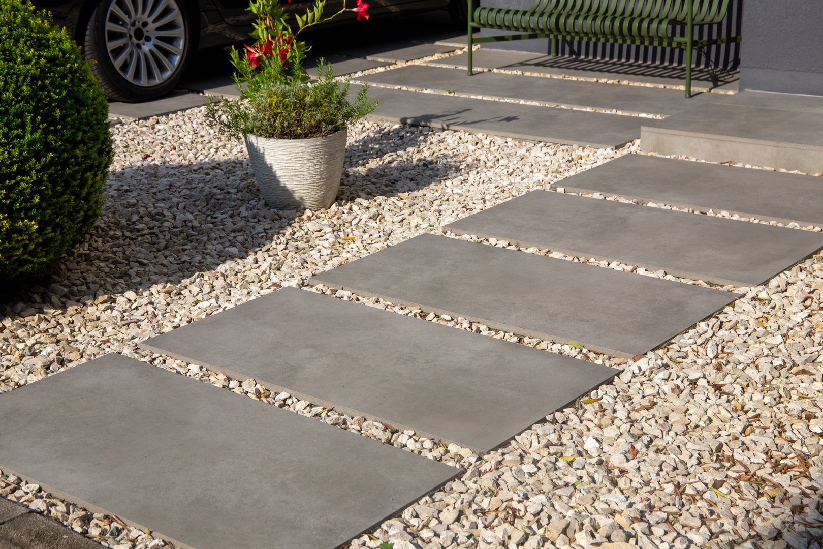 Modern front garden with ornamental chippings, paving slabs and plants in a spherical shape