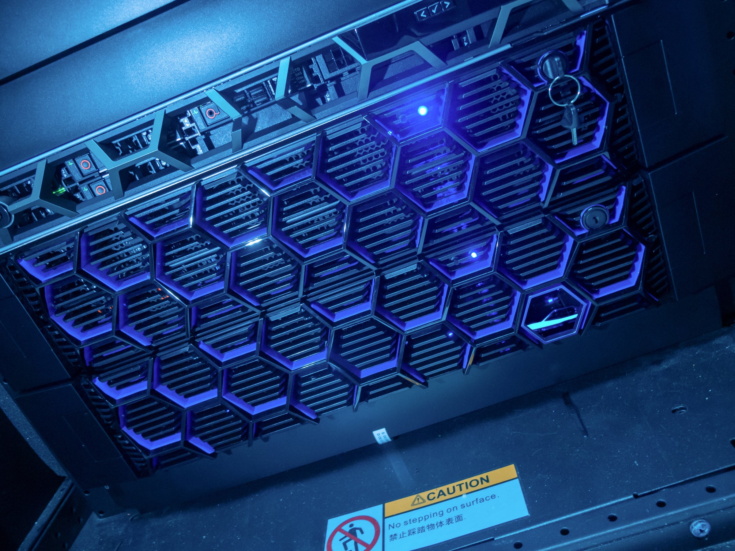 A close-up view of a futuristic rack server featuring blue LED lights and a caution sign, showcasing modern technology and sophisticated design elements in a professional setting.