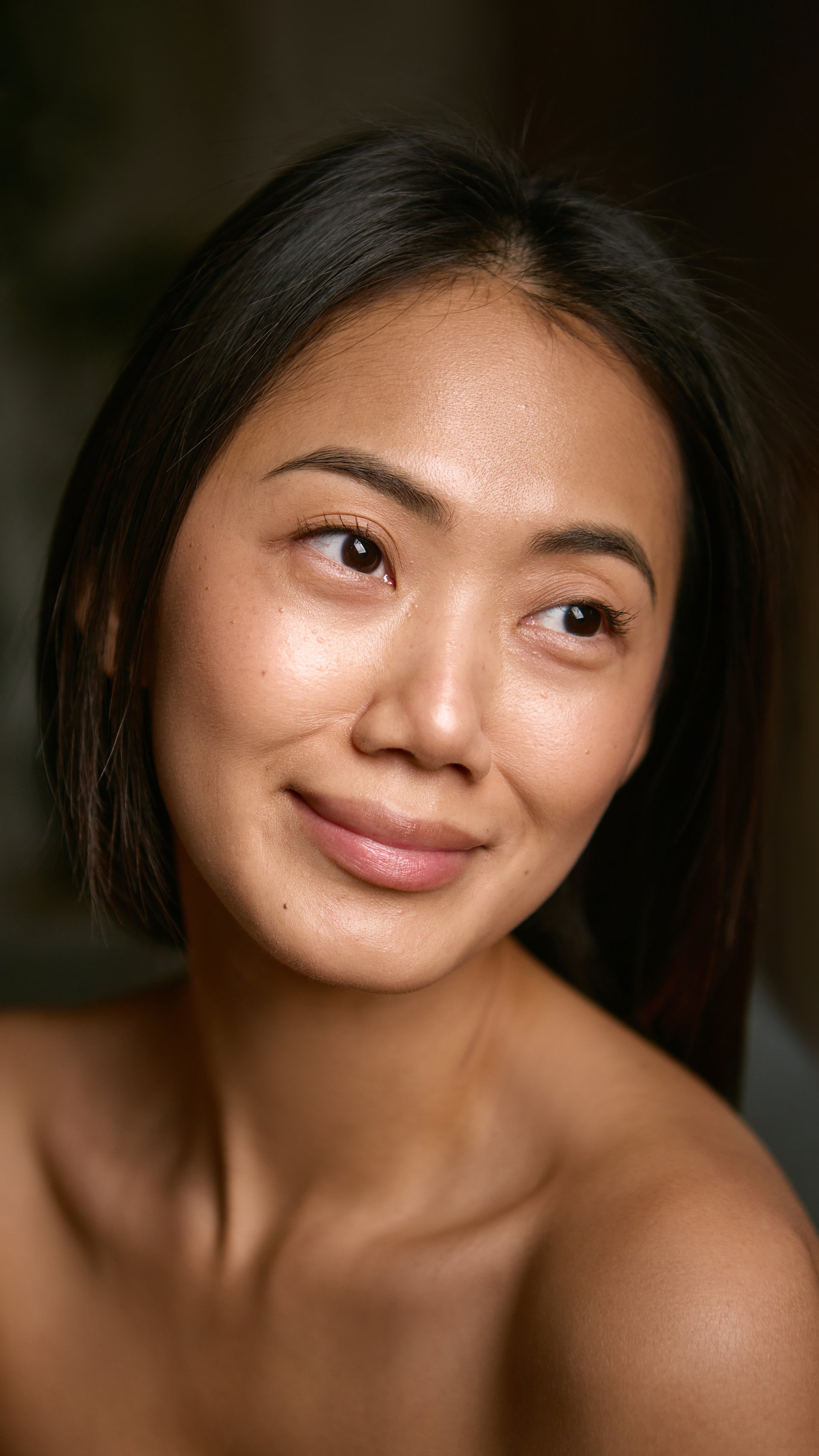 Young woman smiling softly with natural healthy skin glow. Concept of dermatological cosmetics, hydration balance, and skin barrier protection for daily self-care.