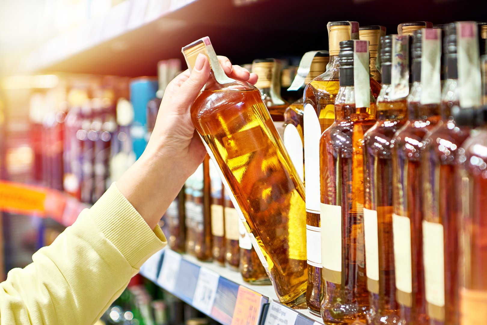 Bottle of whiskey in hand in store
