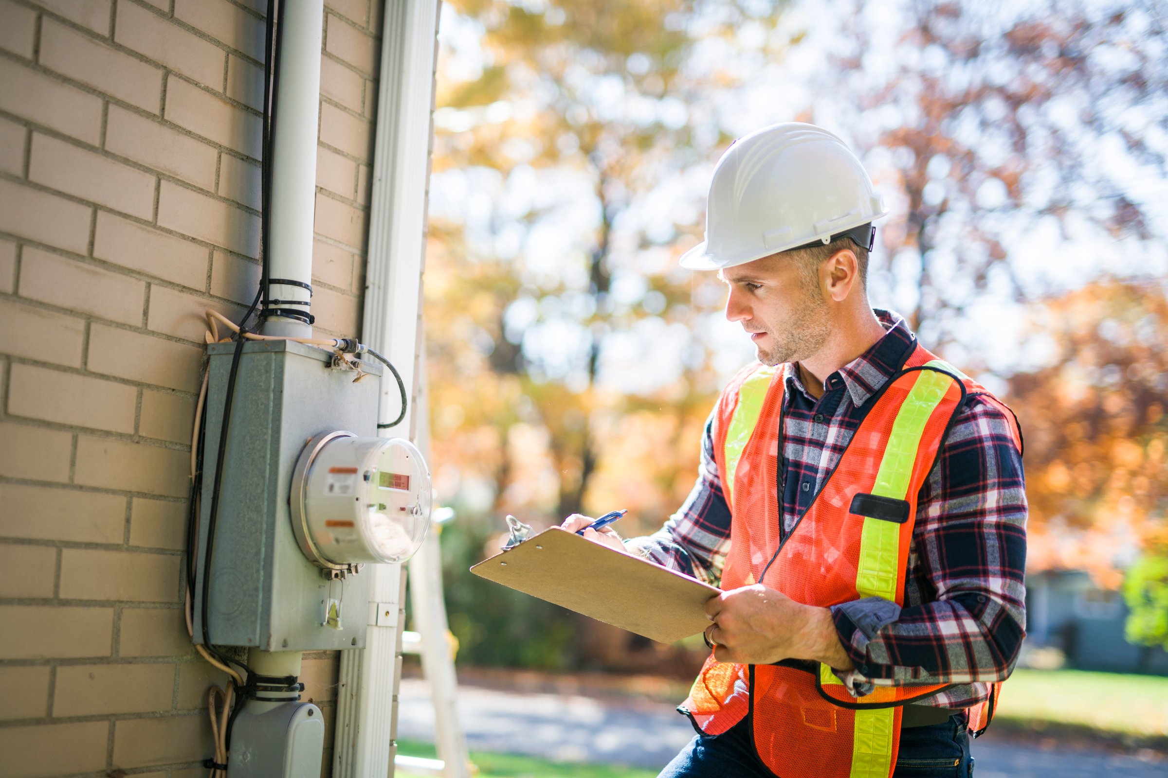 A man with hard hat standing in front of a electric panel