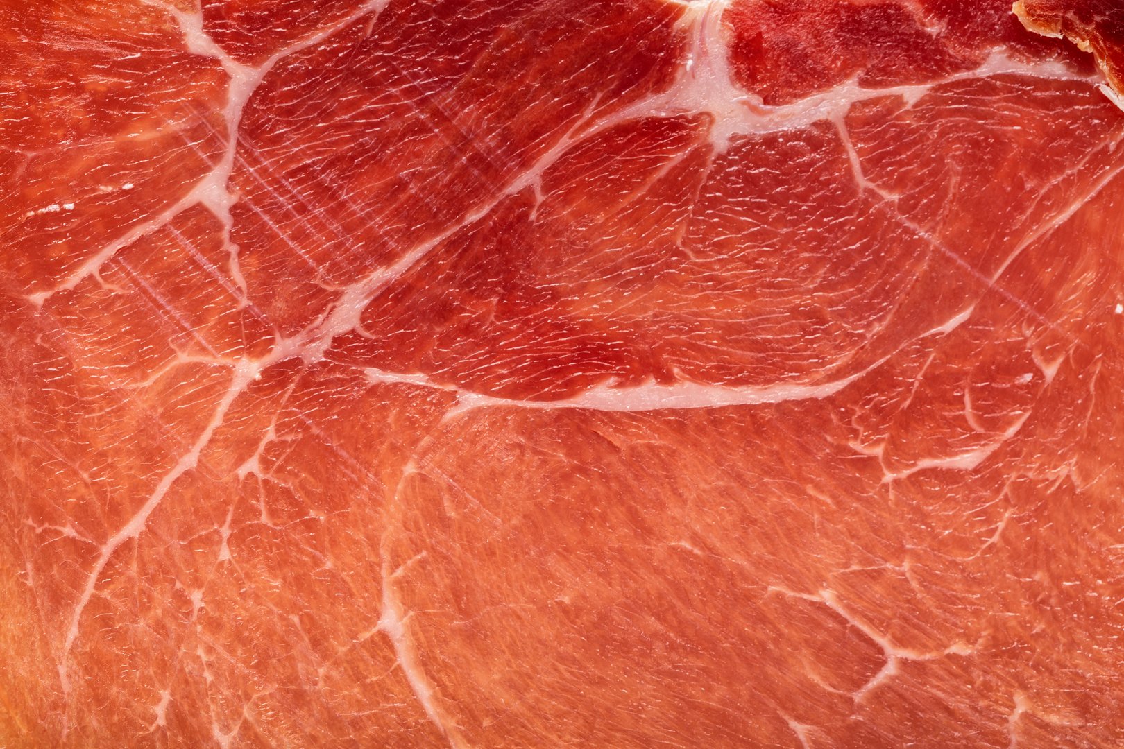 Spanish jamon or Italian prosciutto crudo ham close up. Meat ham macro food background.