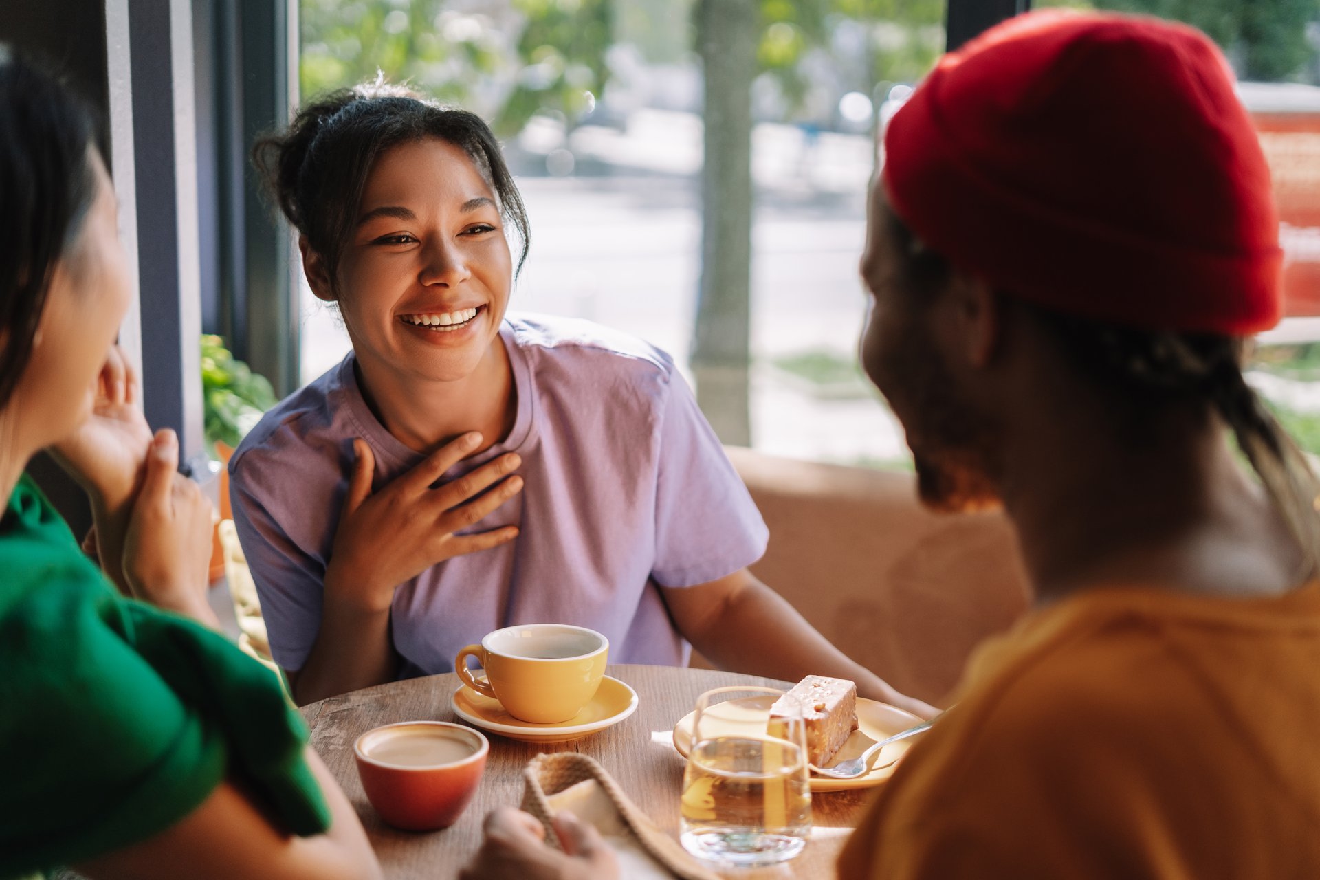 Diverse group of friends enjoying coffee and cake in a bustling cafe, laughing and talking, bonding over shared stories in a modern urban setting