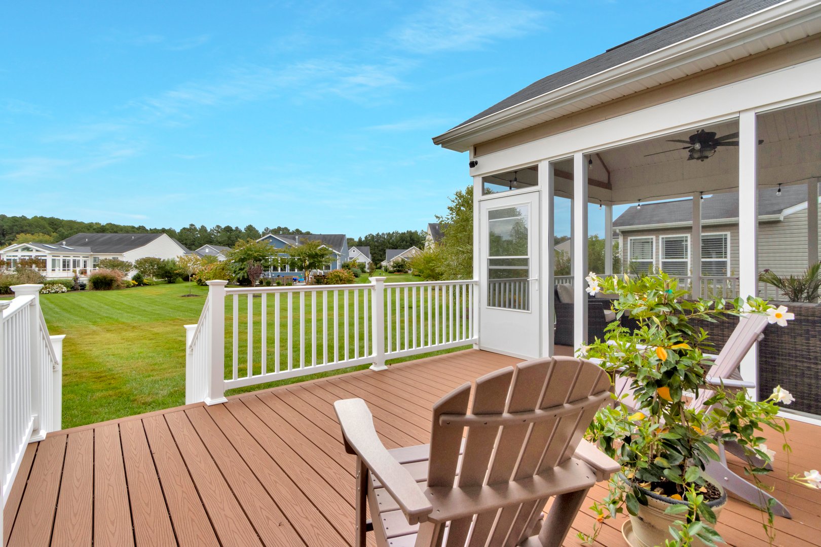 A deck with adirondack chairs looking over green space