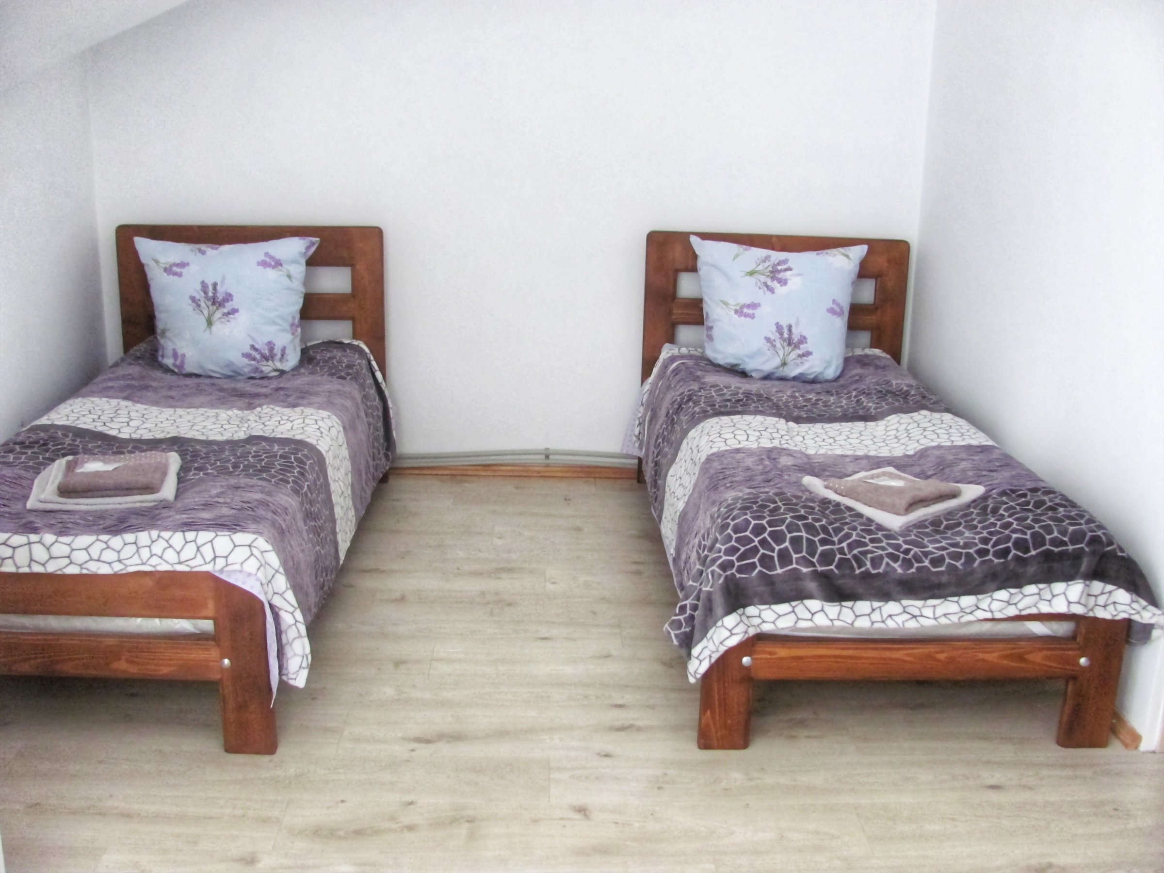 A cozy hotel room with two twin beds, neatly arranged with pillows and towels