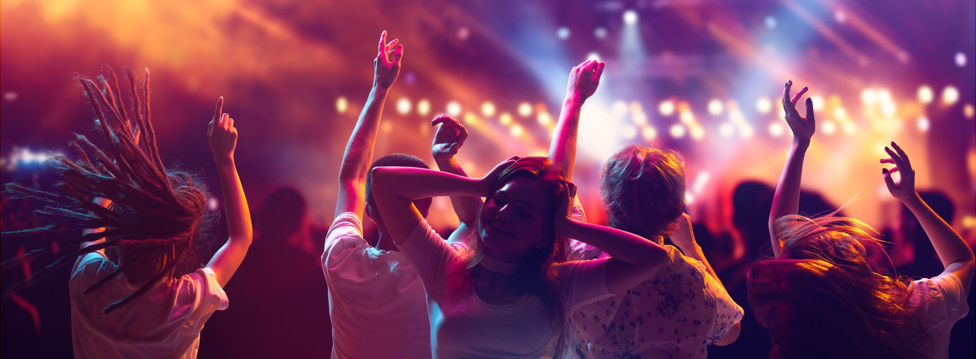 DJ performing in a dimly lit club with colorful lights and lasers illuminating the scene.