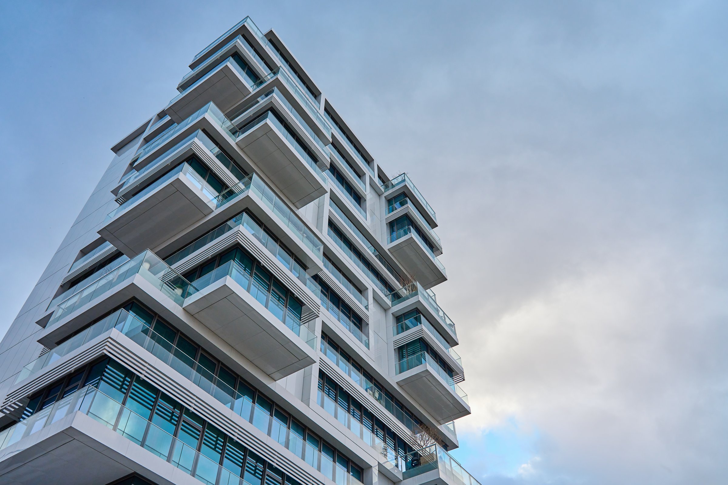 Towering contemporary building in city against cloudy sky, Modern architecture exterior with balconies and glass windows.