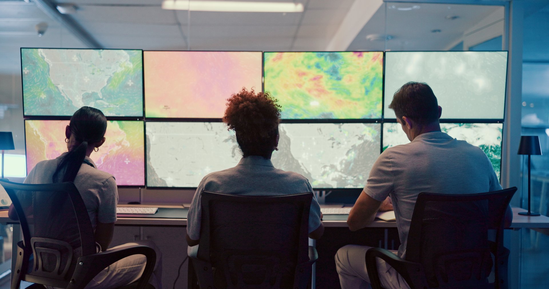 Weather, screen and meteorology with people for forecast, satellite maps or teamwork to track storm. Control room, back or scientists with monitor for broadcast news, pattern review or climate change