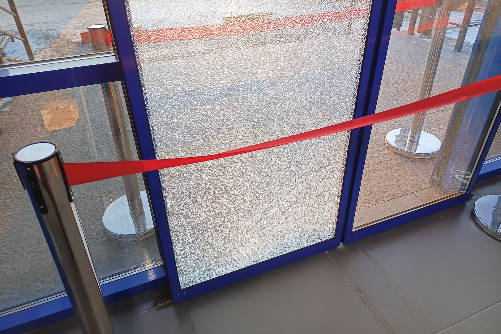 The broken glass on the automatic sliding door is protected by red tape. Repair of automatic doors.