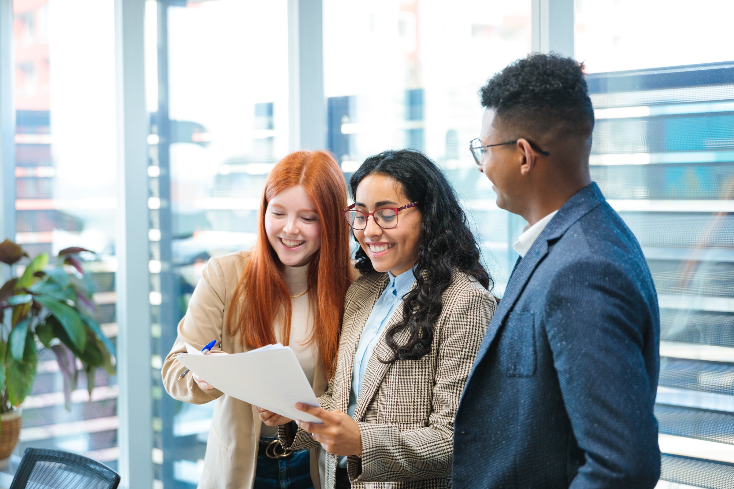 Young businesspeople reviewing documents and smiling in a bright office space