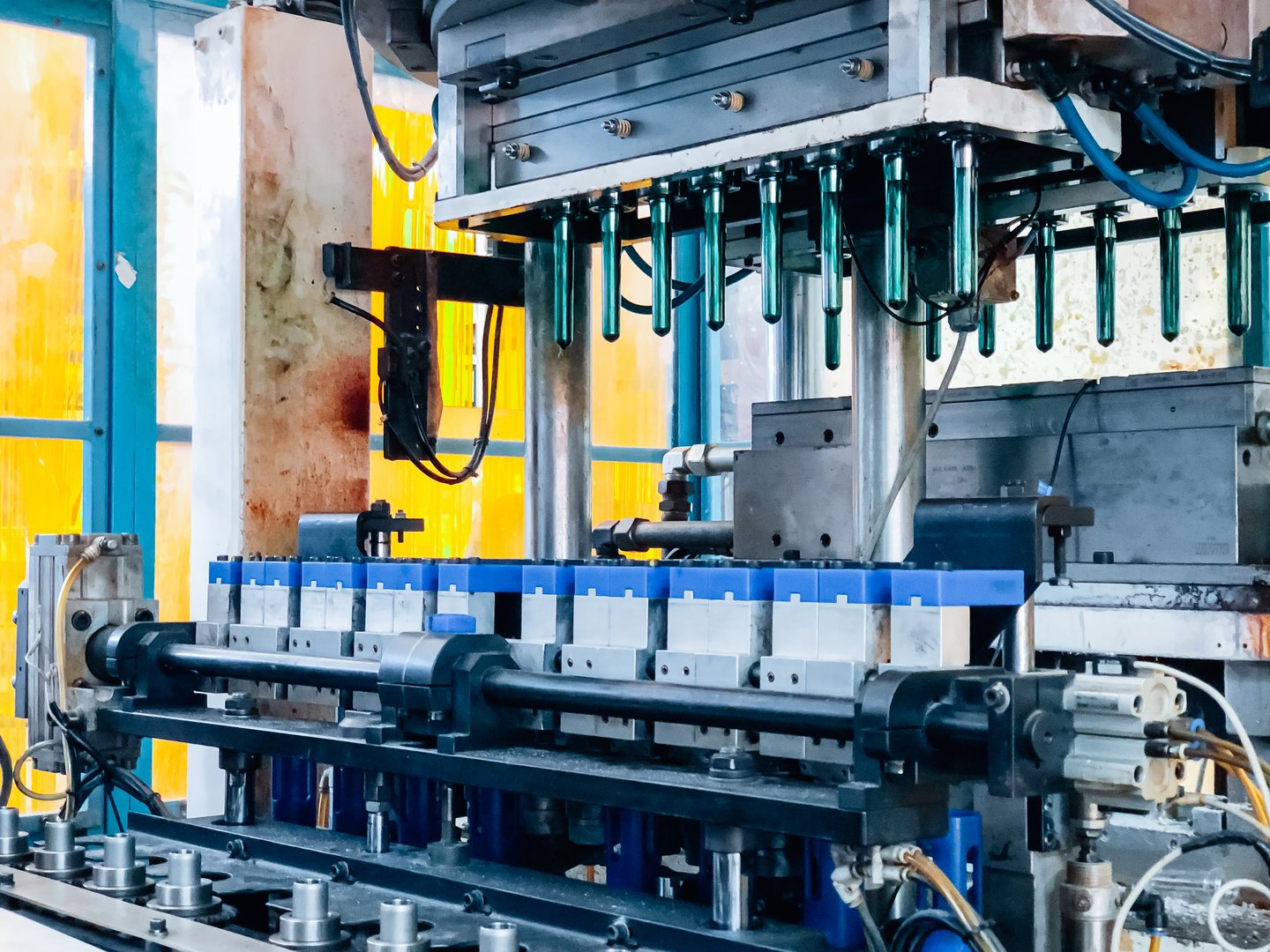 Blow molding machine producing clear plastic bottles on factory production line.