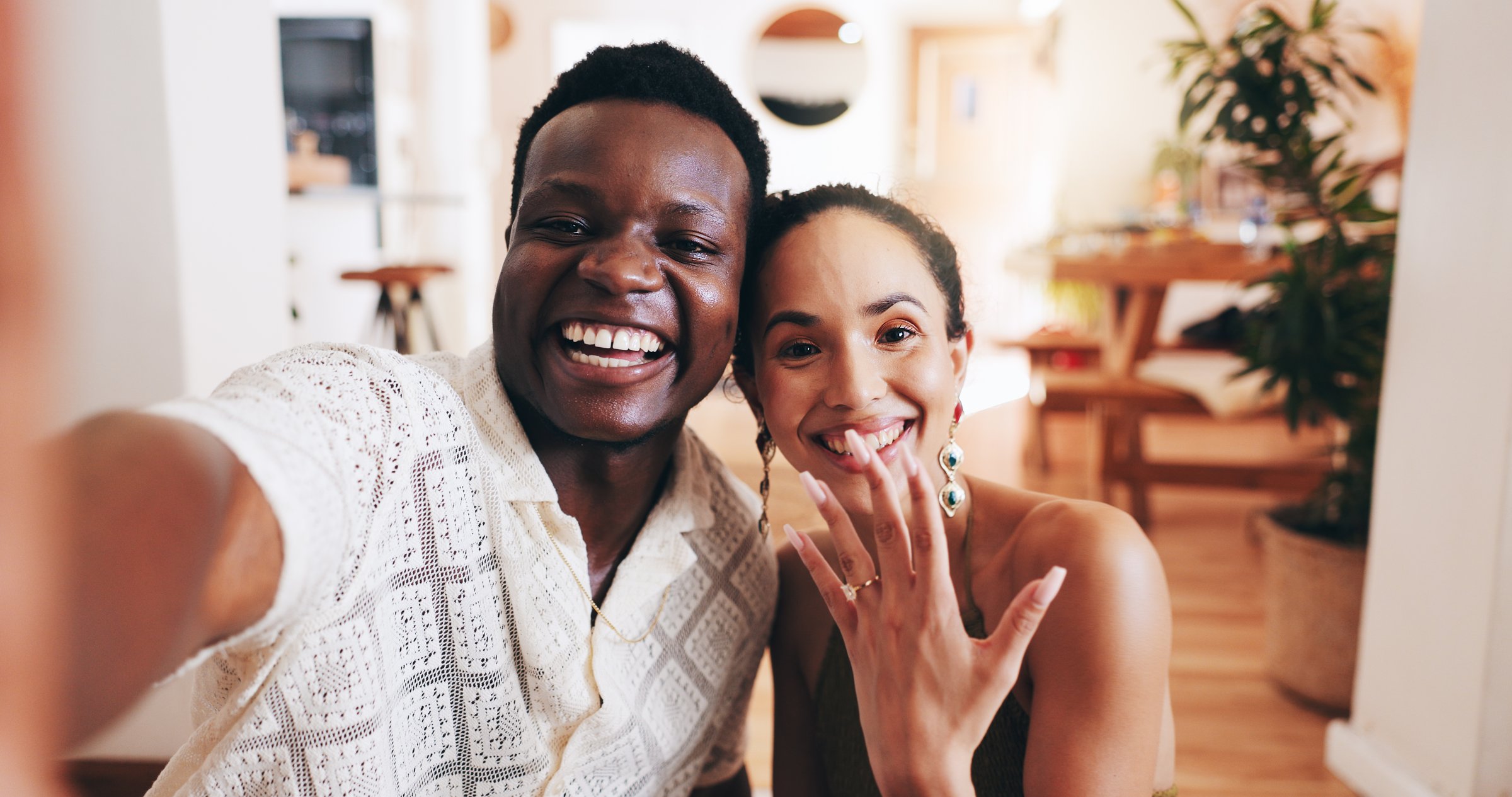 Happy, portrait and interracial couple with selfie for marriage proposal, ring or save the date at home. Excited man, woman or lovers with smile in joy for picture, memory or yes together at house