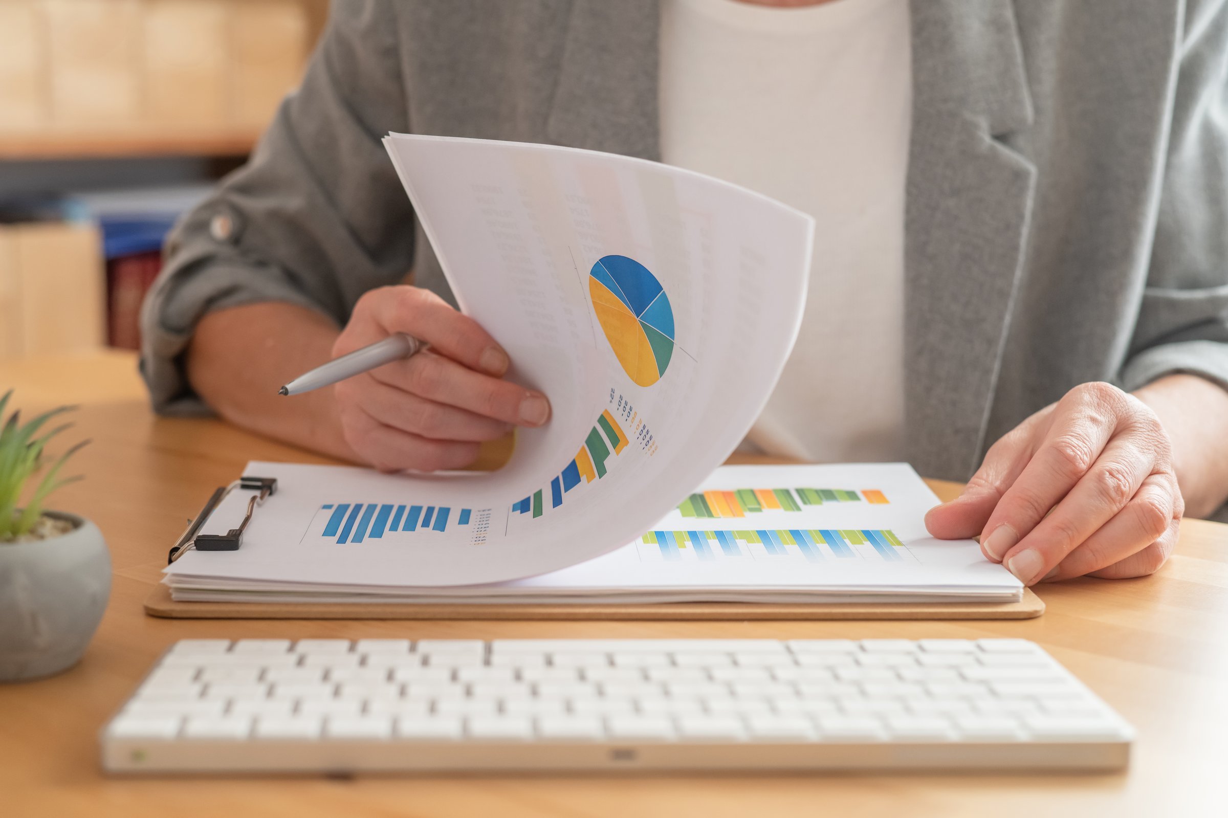 Businesswoman reviewing financial reports presenting data, charts, and graphs while working at a desk, focusing on analysis, strategy, and business growth