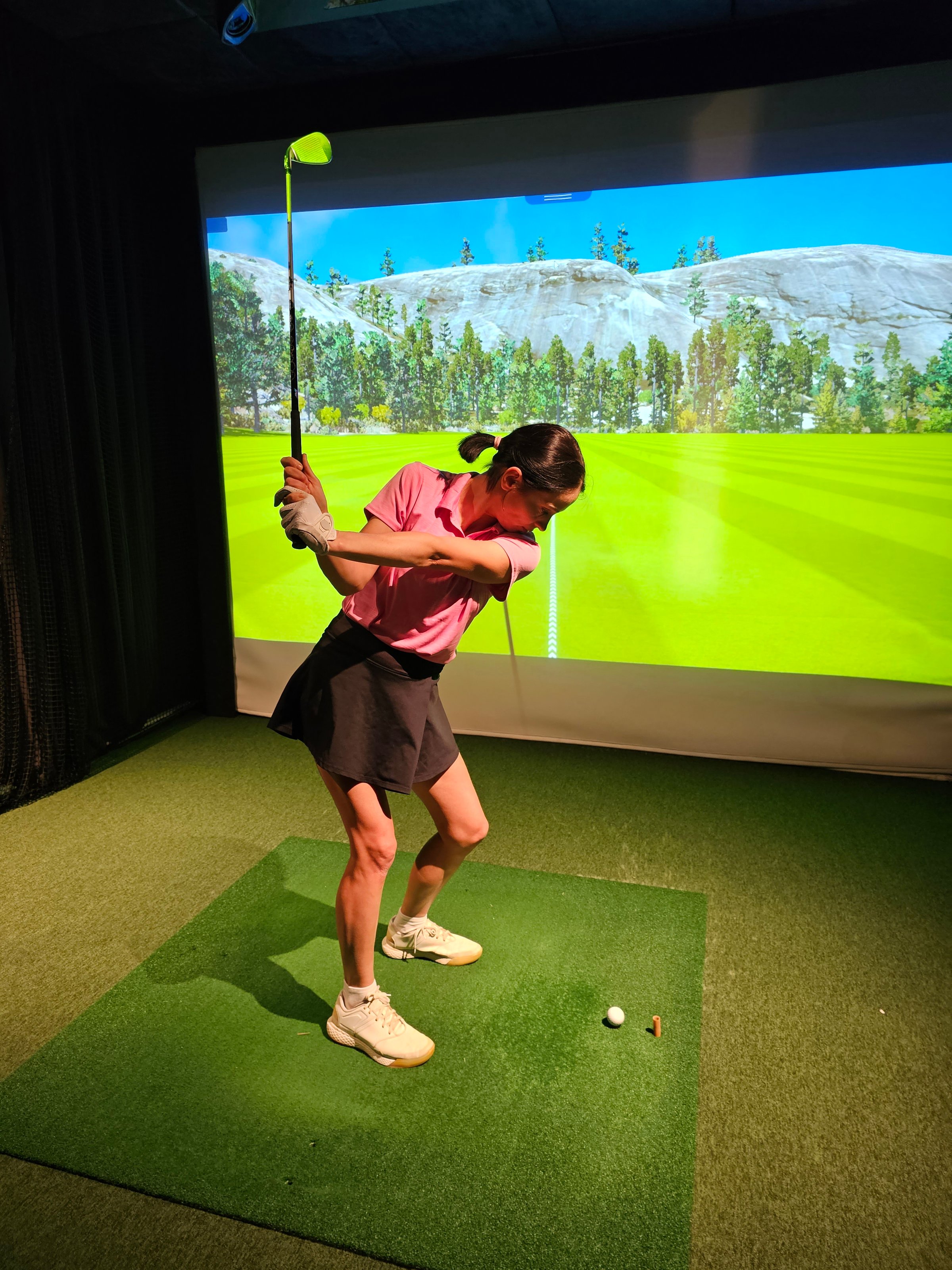 Golfer prepares to swing in indoor simulator