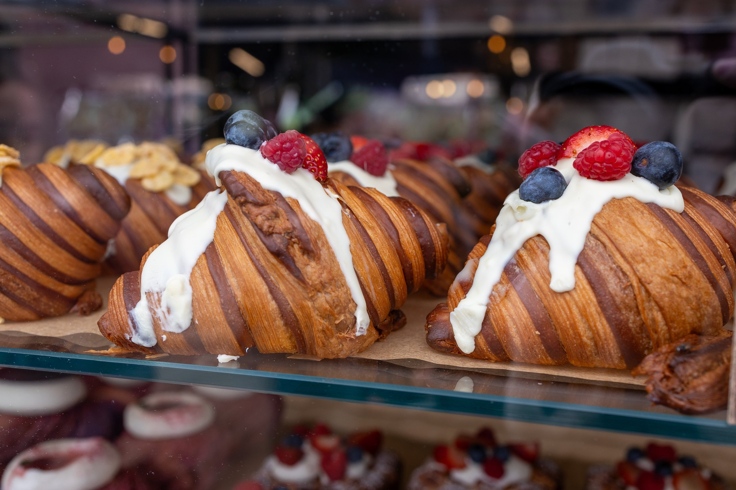 Artisan croissants with cream and fresh berries in bakery display